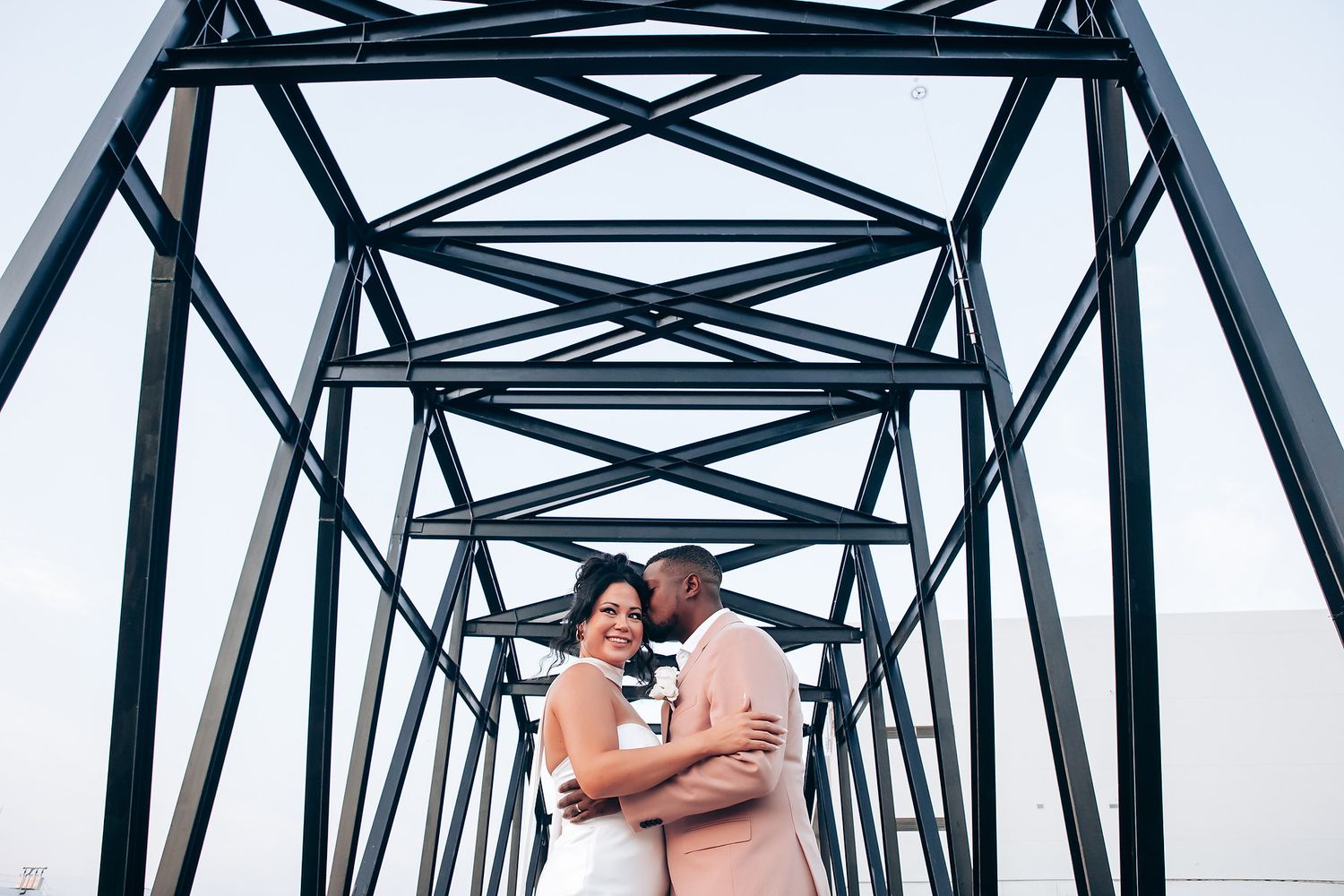 A couple shares an intimate moment on a steel bridge structure.
