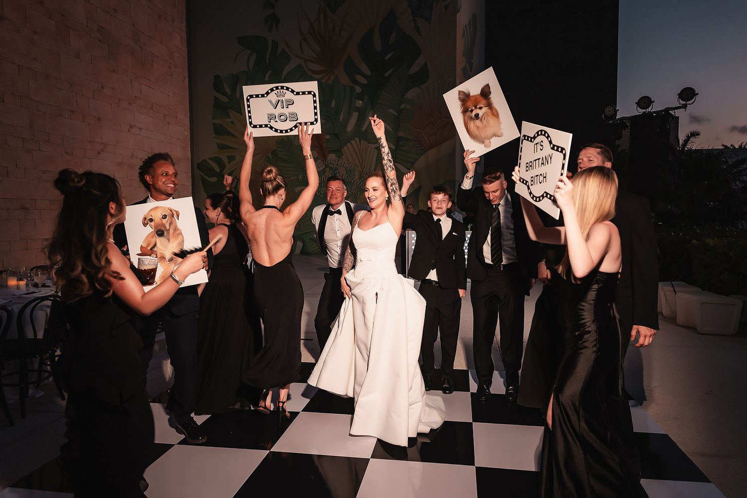 Wedding reception celebration with guests dancing on a black and white checkered dance floor.