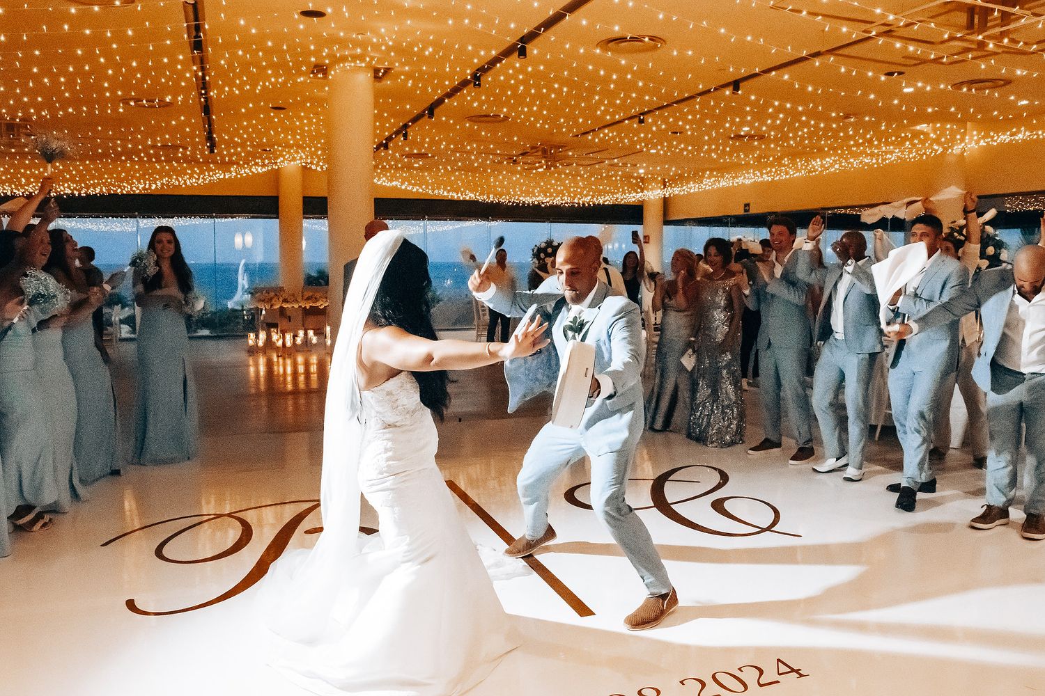 Wedding guests dancing on an illuminated dance floor under sparkling ceiling lights.
