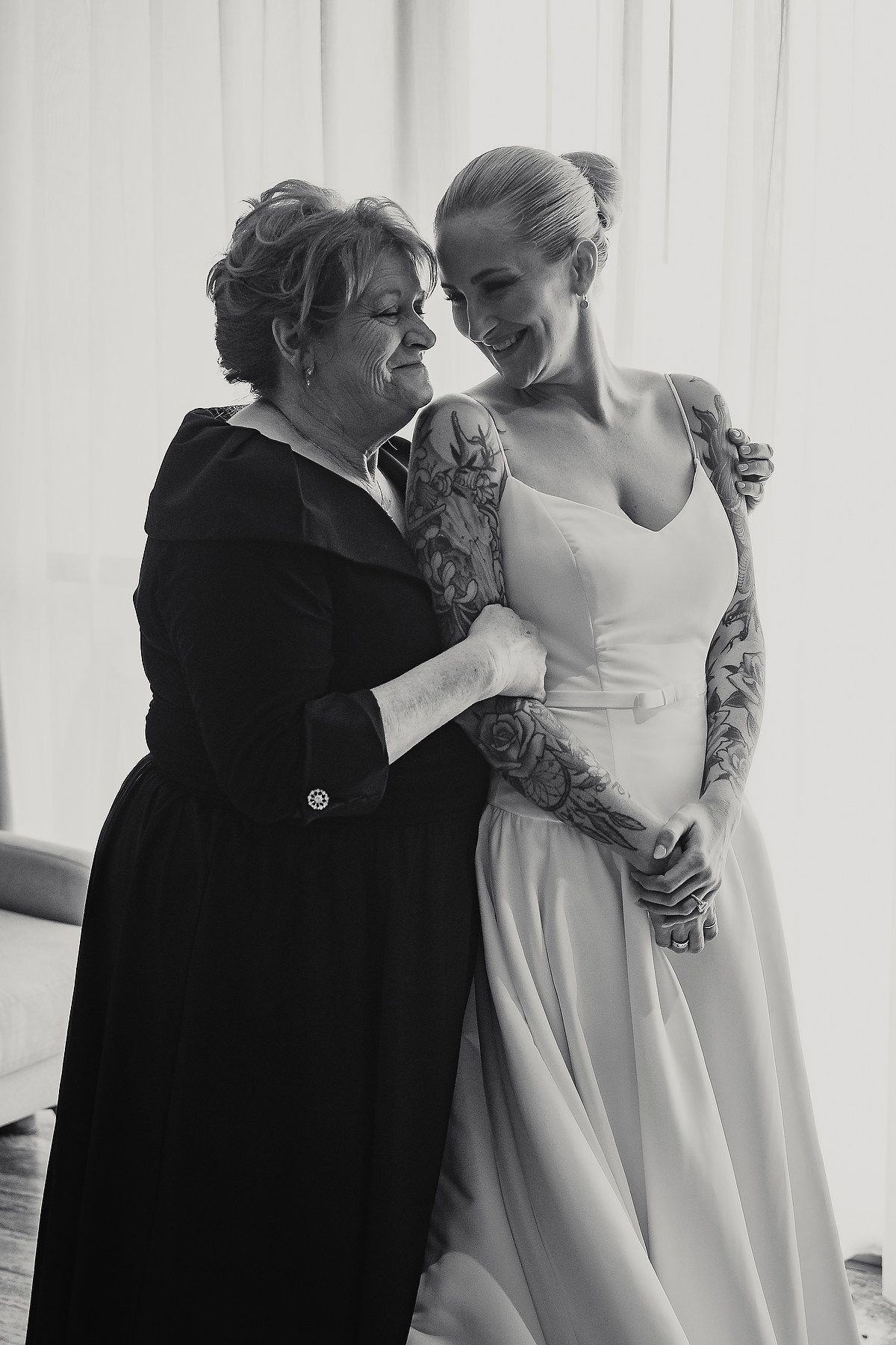 Two people share an intimate moment in formal attire against a white backdrop.