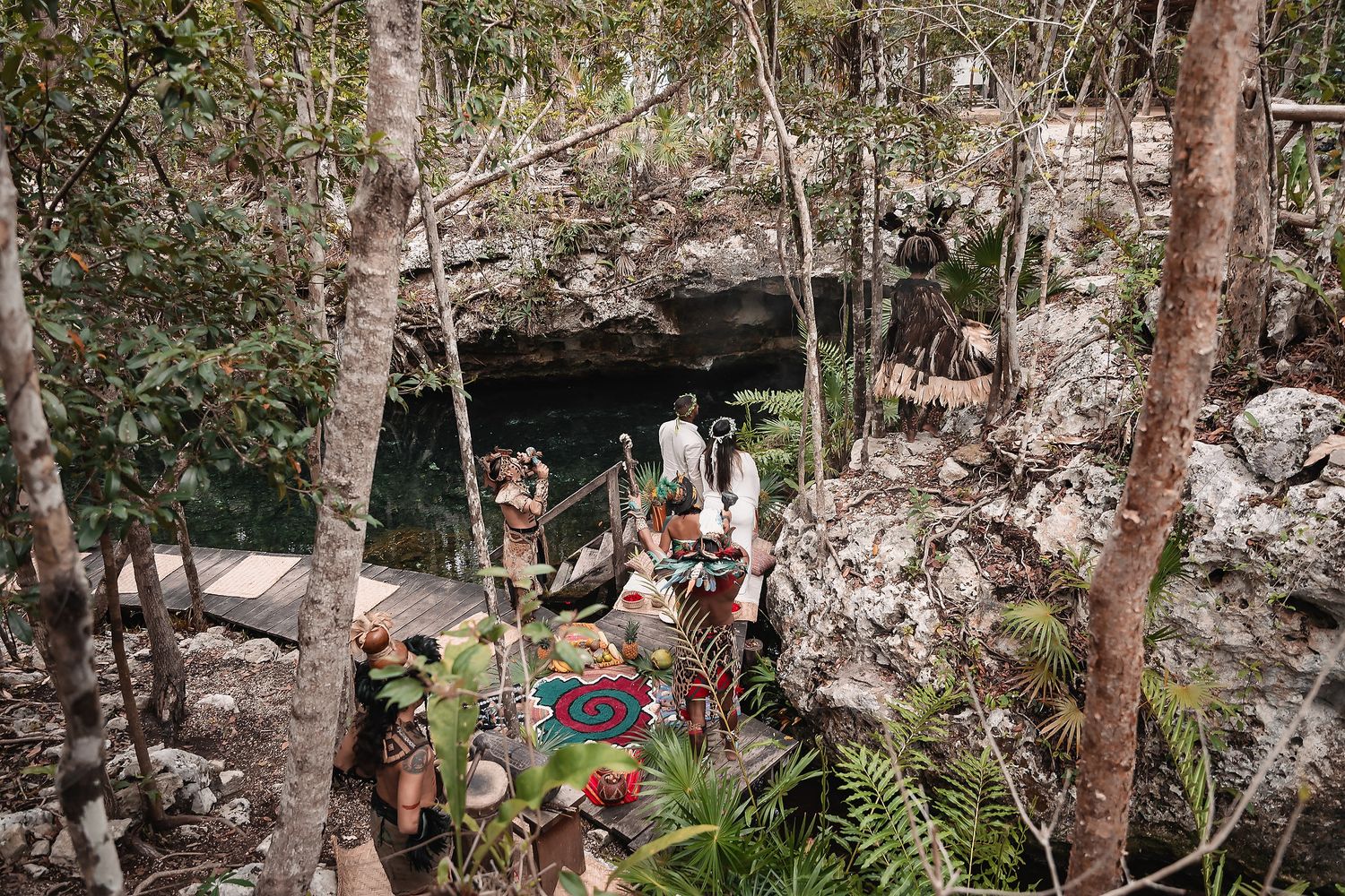 Traditional ceremony setup at entrance of a cenote cave surrounded by lush vegetation in Mexico.