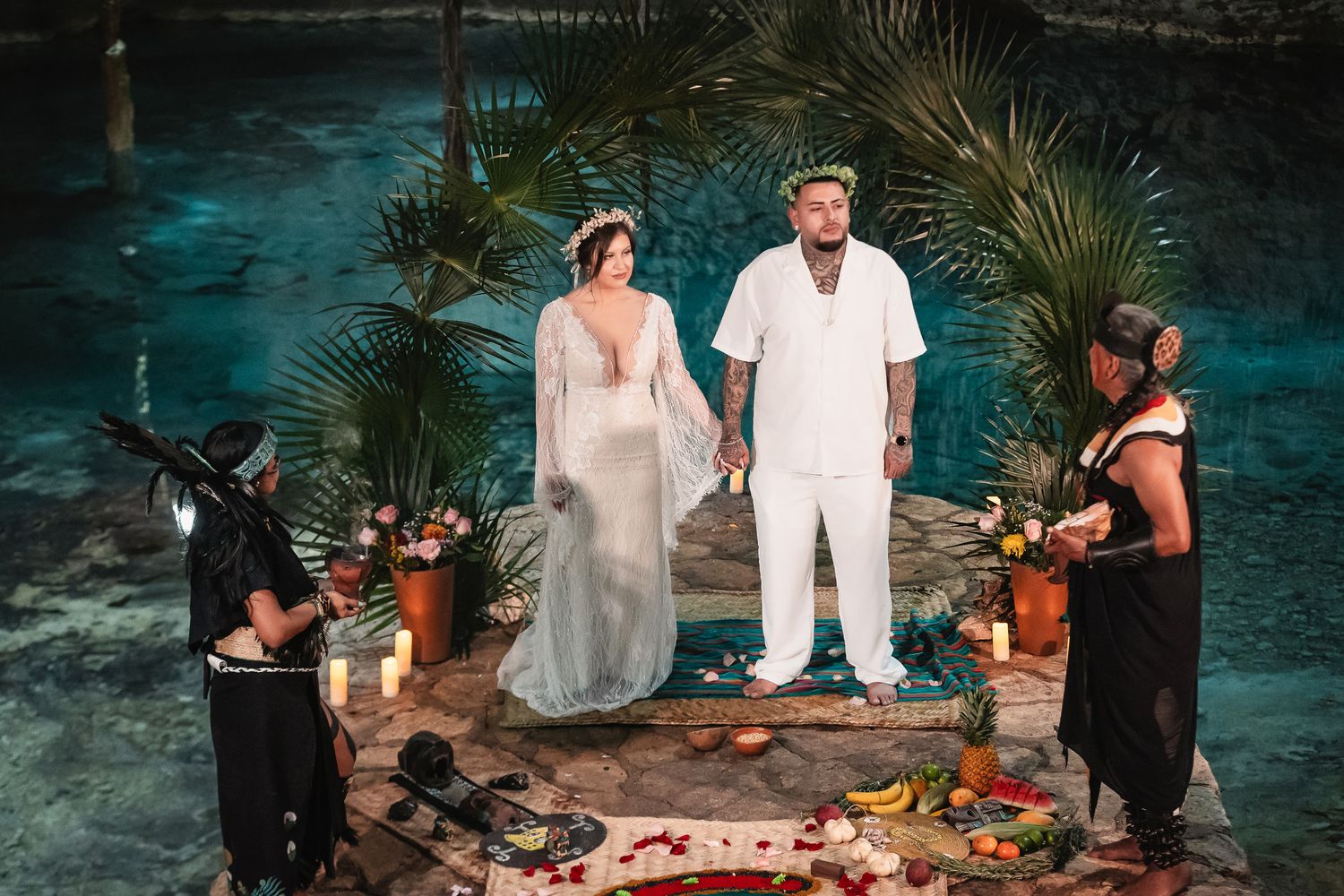 Romantic cave ceremony setup with guests gathered around turquoise waters and candlelit decorations.