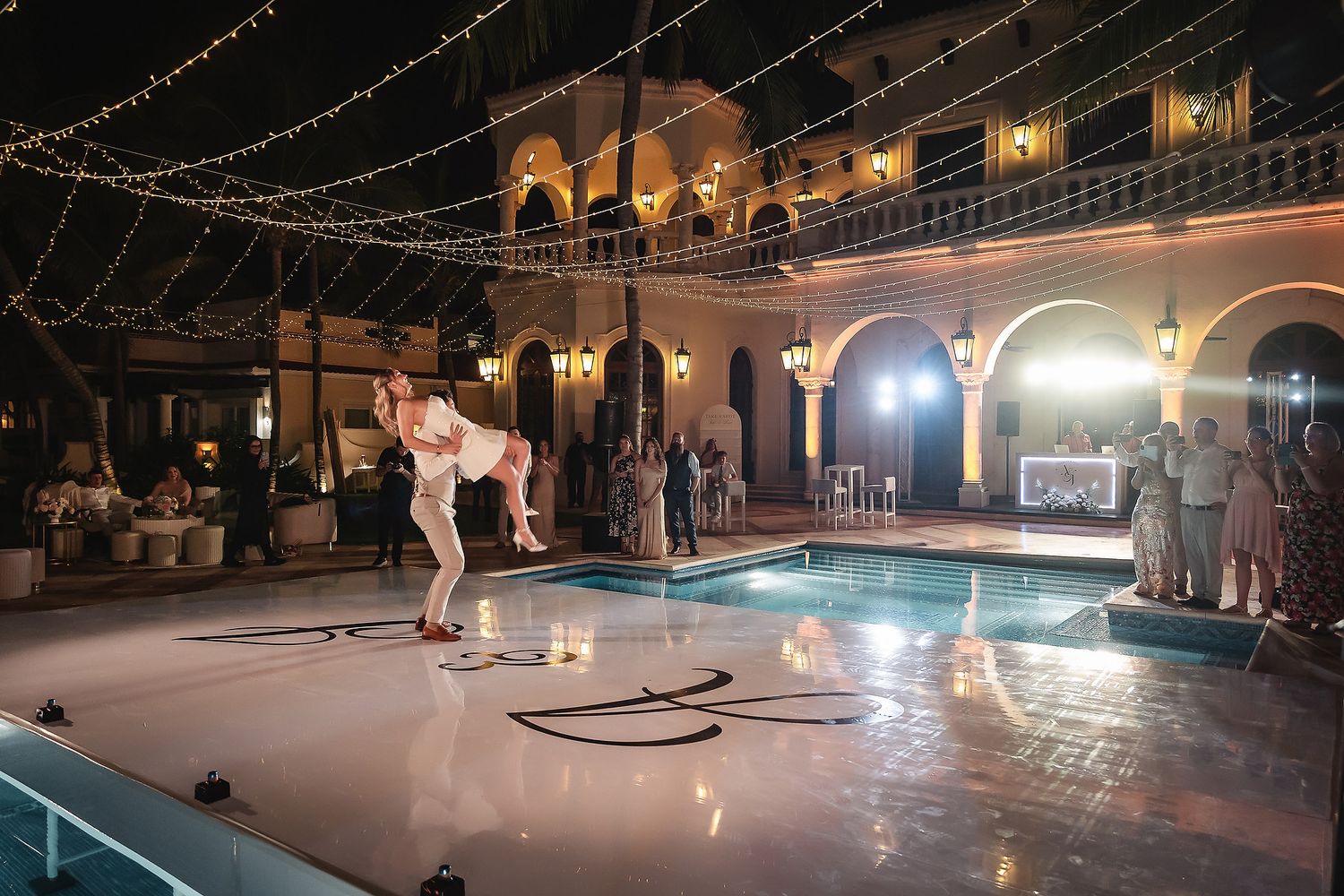 Elegant outdoor wedding reception space with string lights and pool deck.