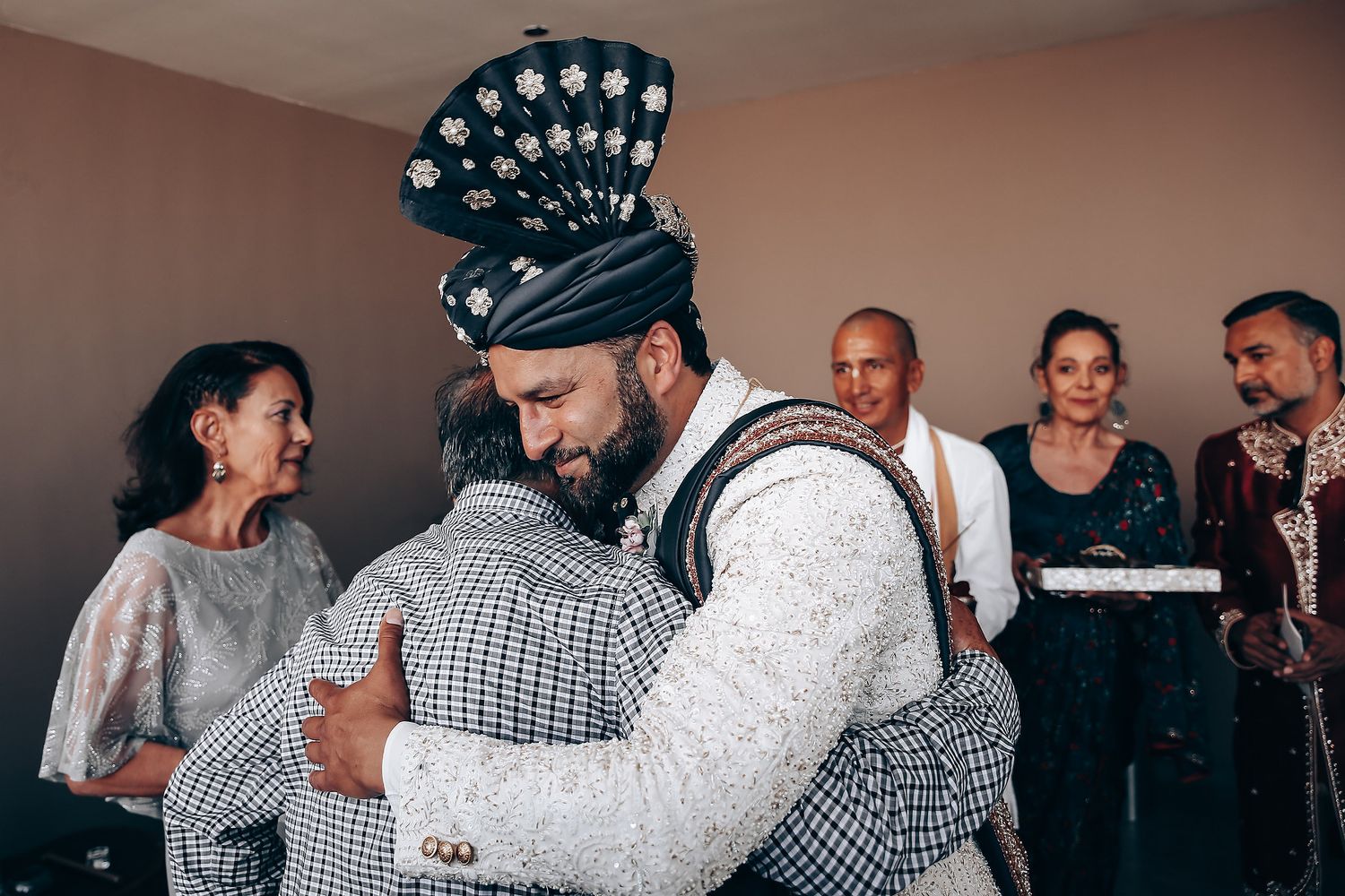 Wedding guests embrace and dance together during a joyful celebration on the dance floor.