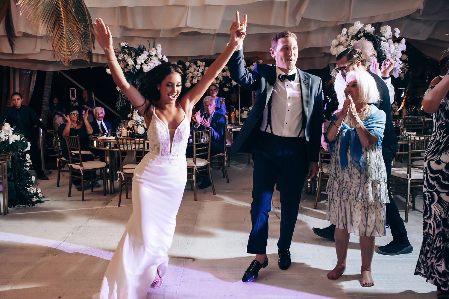 Celebratory moment on a wedding dance floor with guests cheering.