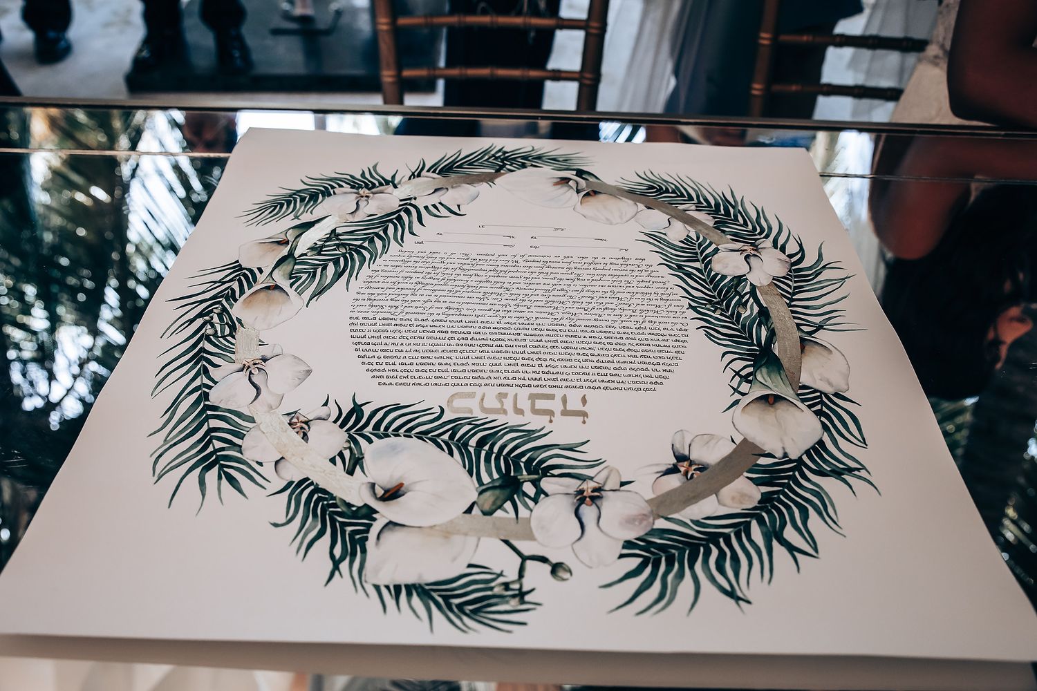 Decorative palm fronds arranged around text on white table settings at formal event.