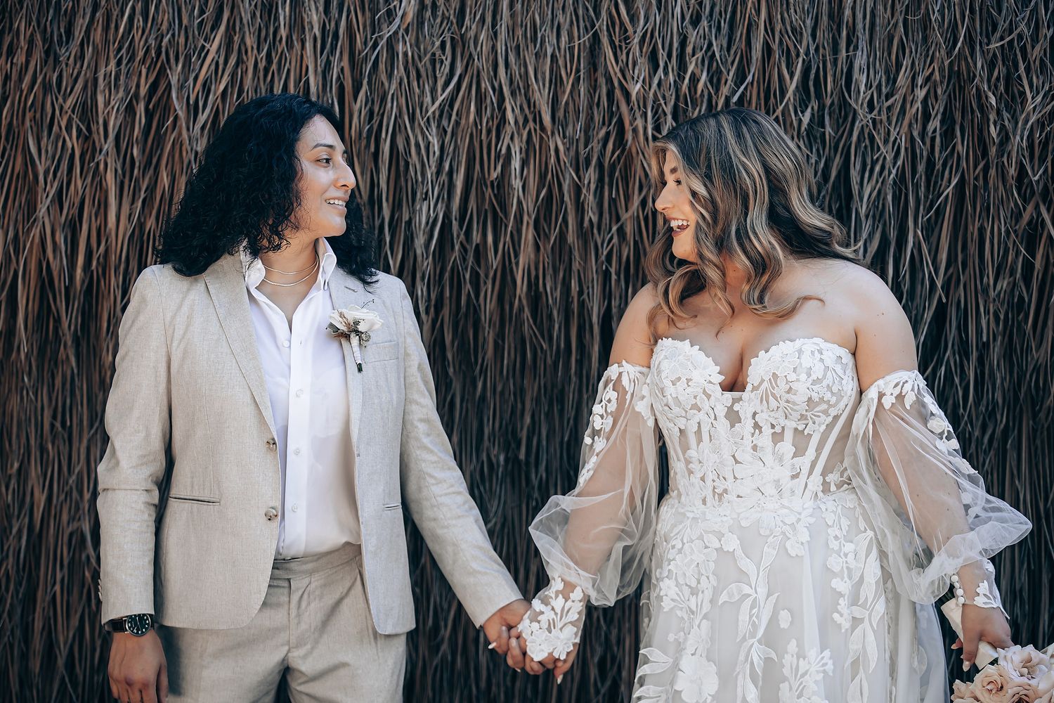Romantic beach wedding couple shares intimate moments in front of natural palm frond backdrop during sunset ceremony.