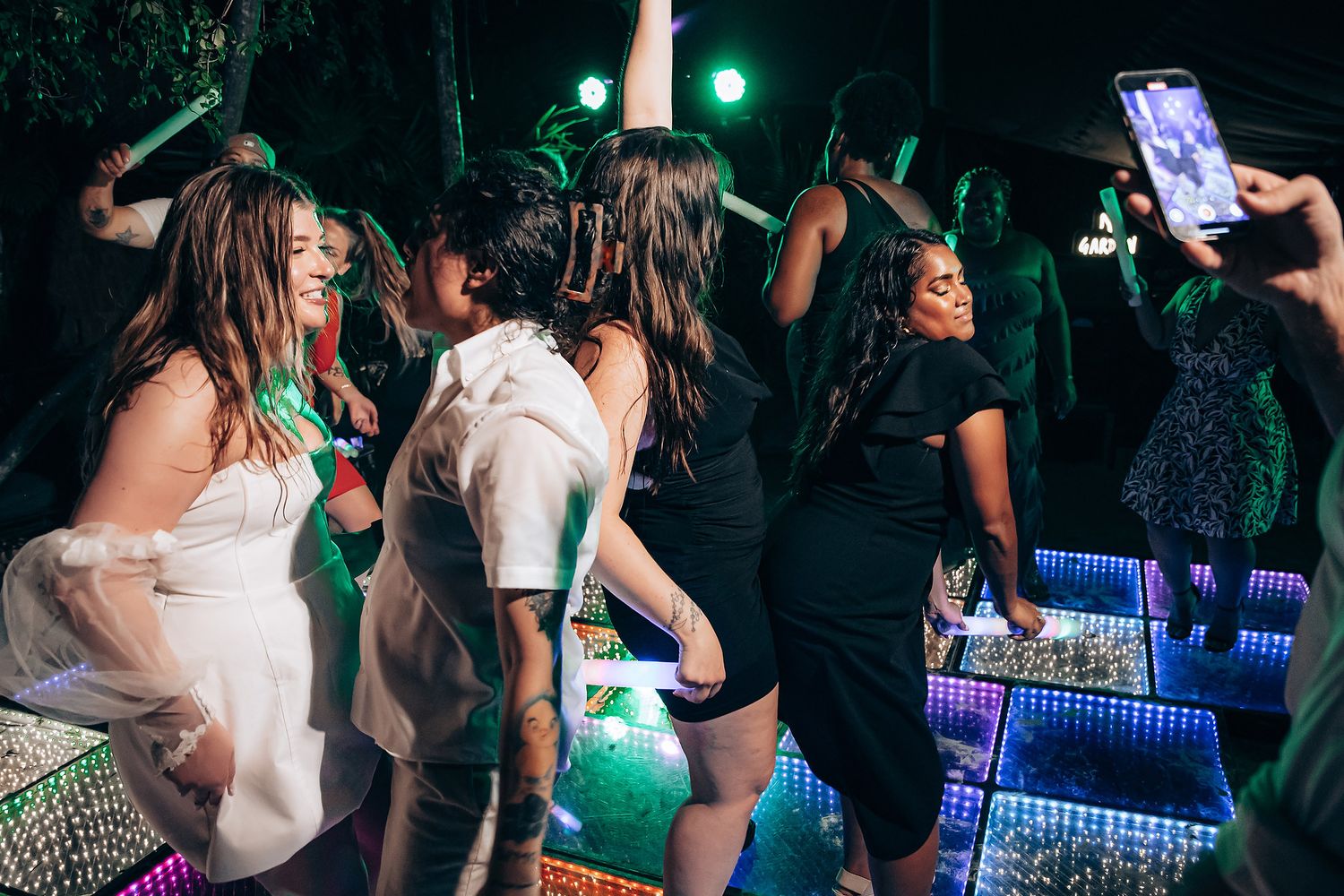 People dancing and socializing at a nightclub with blue lighting and a crowded dance floor.