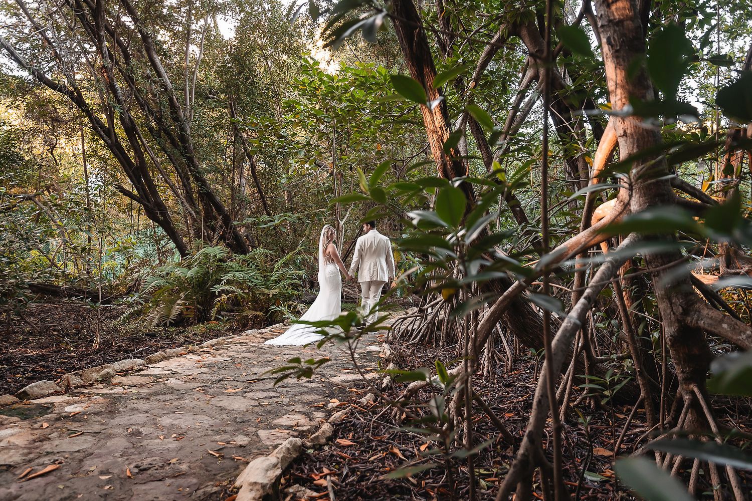 Wedding couple walking through a scenic wooded path during their photoshoot.