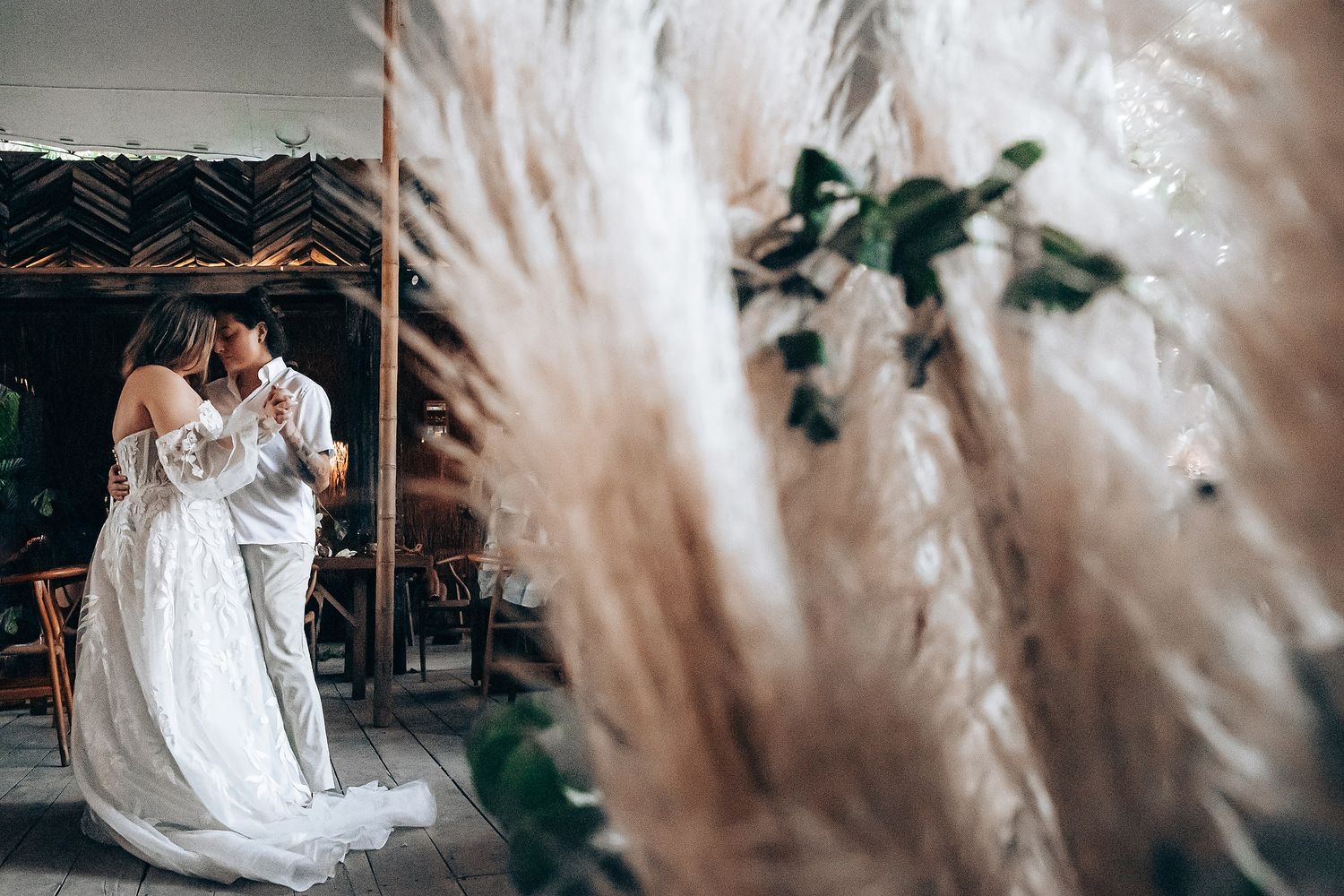 Artistic wedding photos captured through soft brown pampas grass creating a dreamy atmosphere.