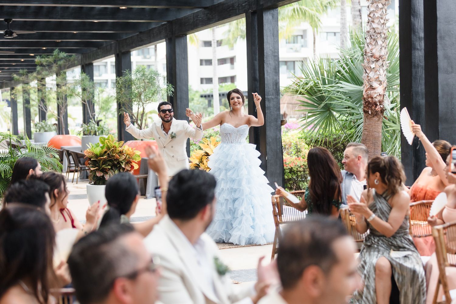 Bride and groom dancing joyfully at outdoor wedding reception with guests celebrating around them.