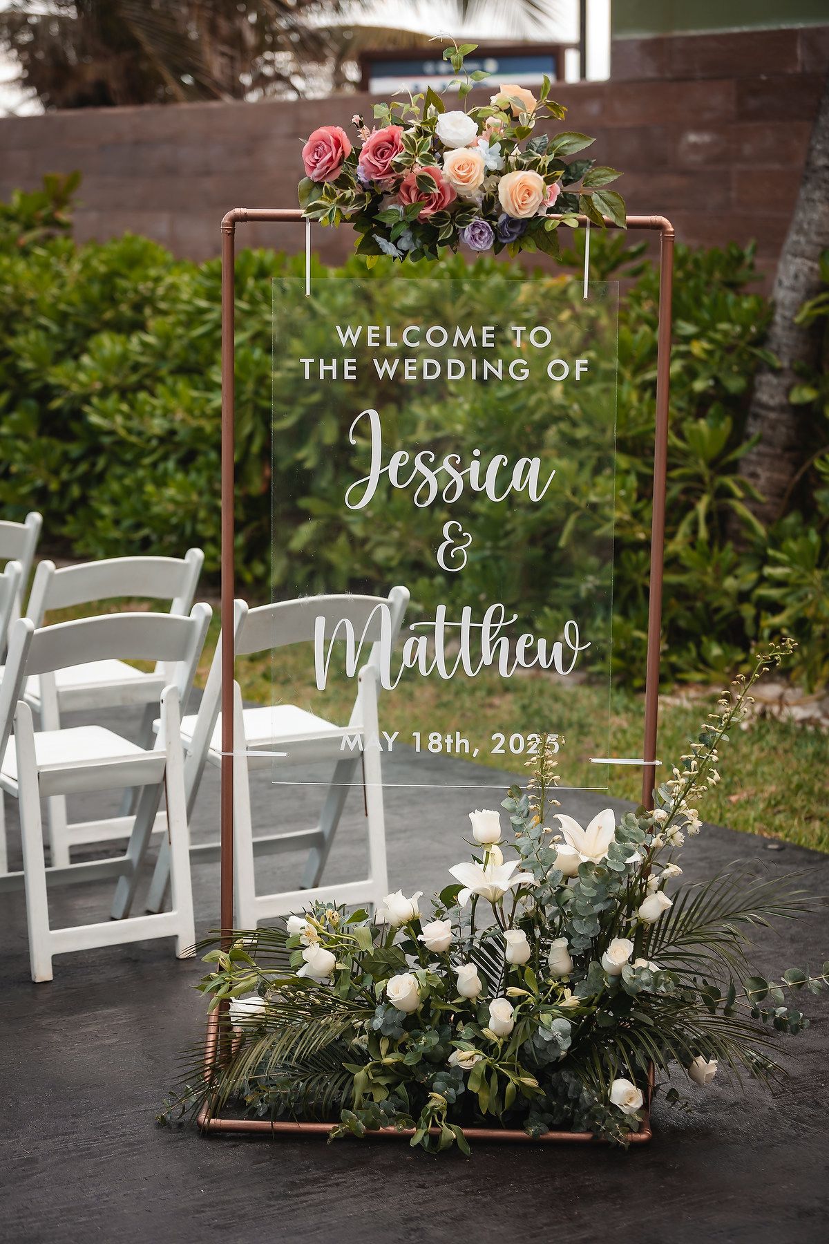 Elegant acrylic wedding welcome sign for Jessica and Matthew May 18th 2023 framed in rose gold with flowers.