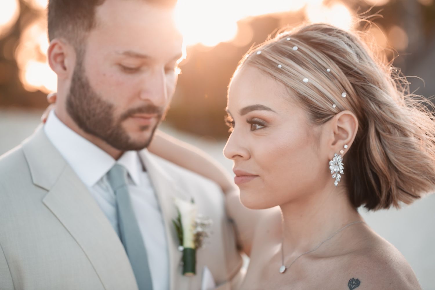 Close-up of bride and groom at golden hour wedding, bride wearing crystal hair pins and chandelier earrings.