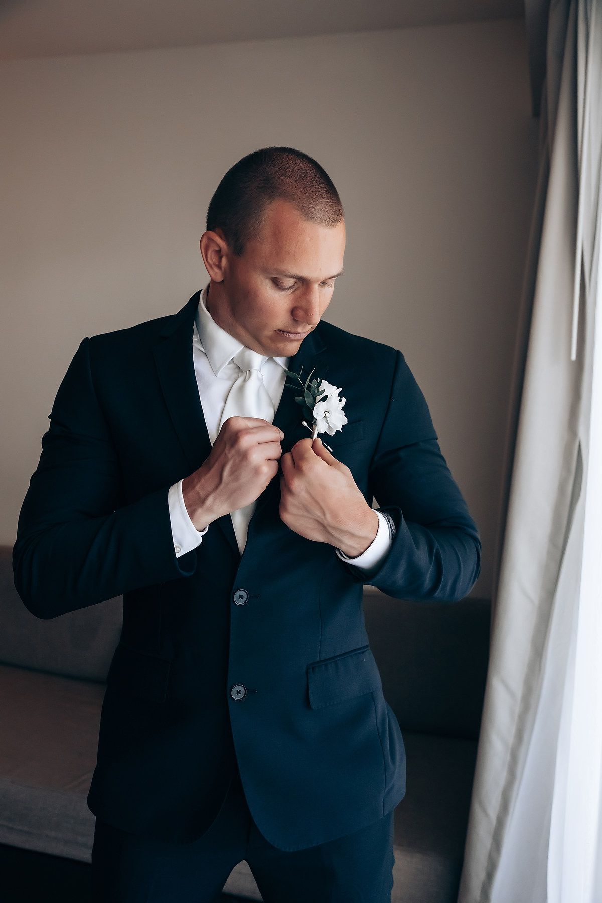 A sequence of photos showing someone in a dark suit adjusting their boutonniere before a formal event.