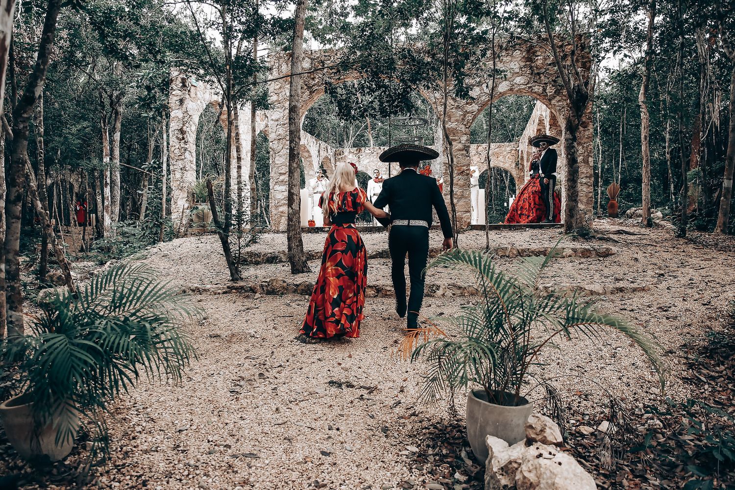 Gothic-inspired outdoor photoshoot featuring red and black costumes among stone ruins and natural foliage.