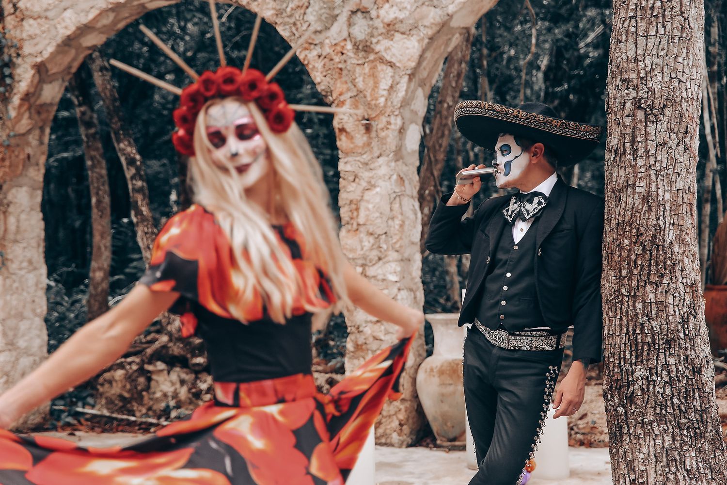 Dramatic outdoor scene with gothic-styled figures in formal wear against a stone architectural backdrop.