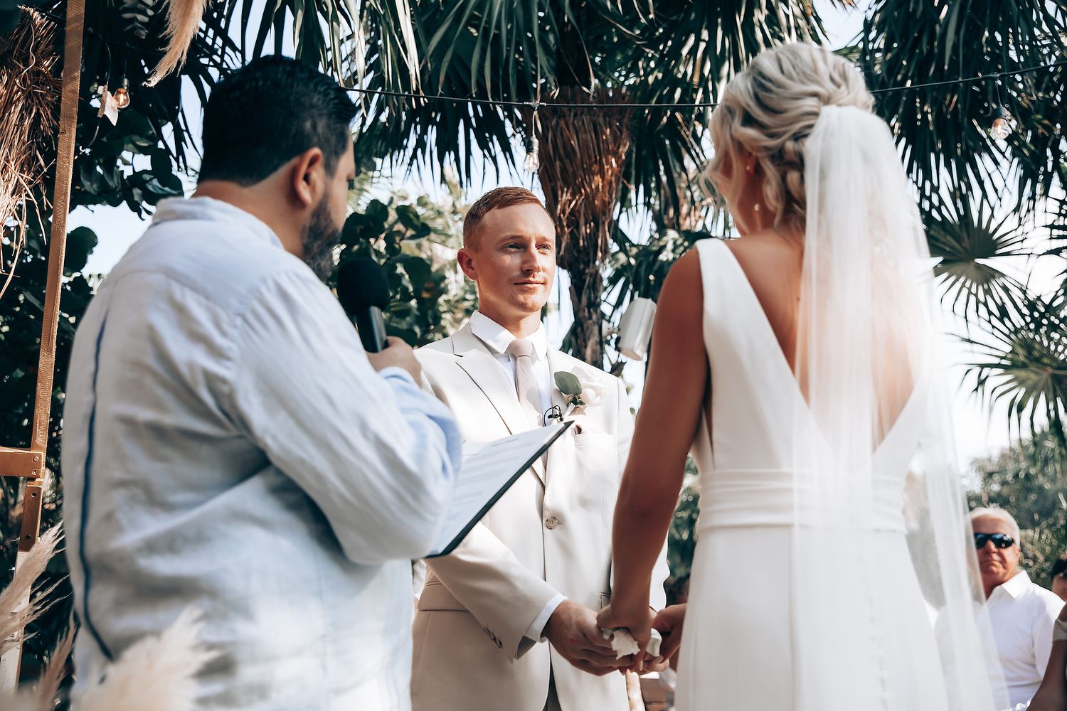 Wedding ceremony moments captured in a lush tropical garden setting with palm trees.