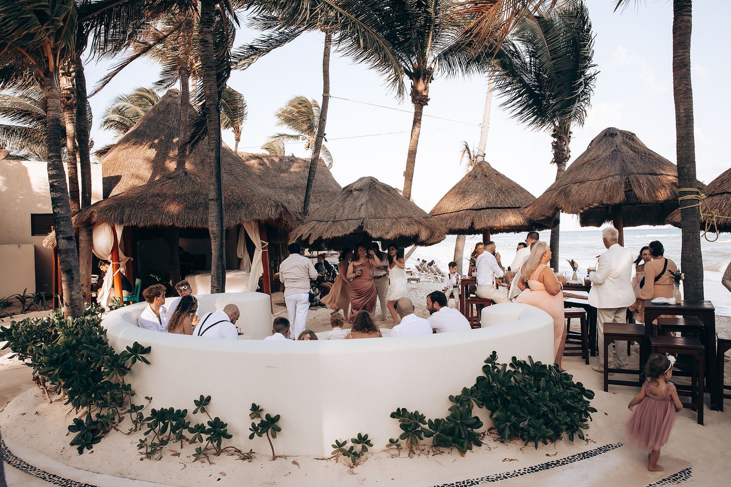 Beachfront wedding reception setup with thatched roof palapas.