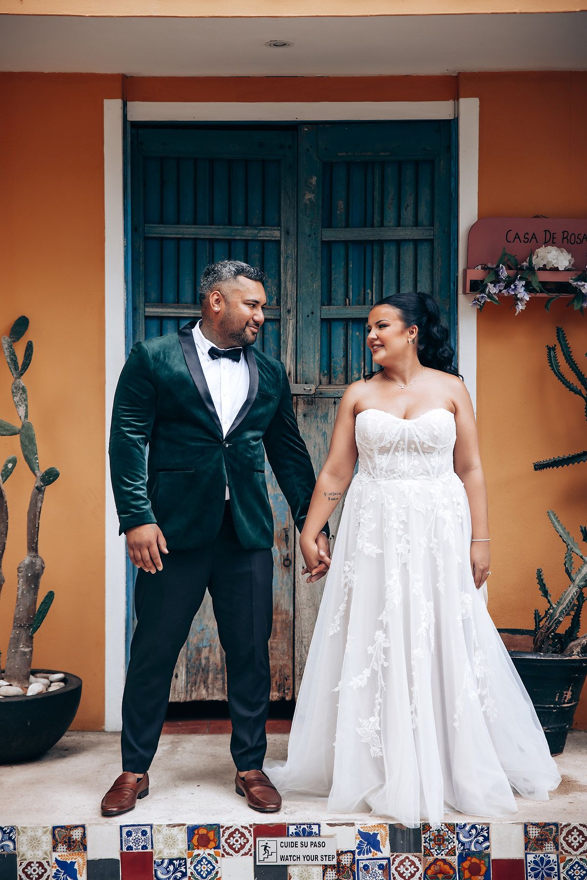 A couple poses playfully against a colorful wall with decorative tiles.