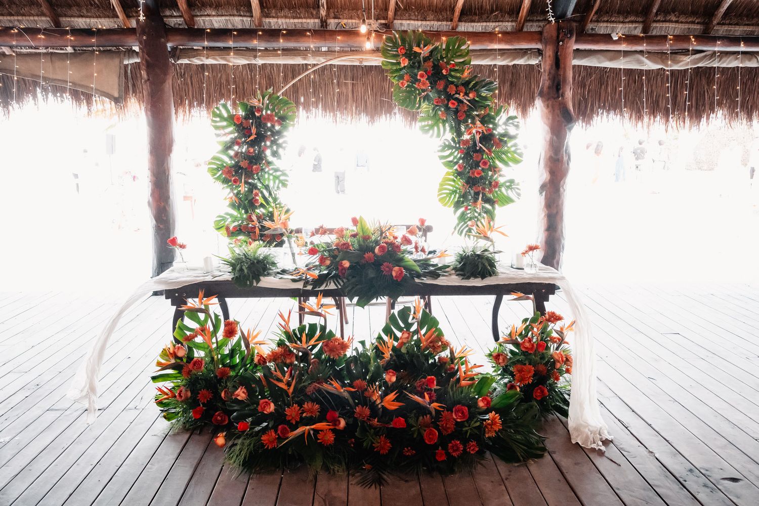 Elegant tropical wedding sweetheart table adorned with lush orange and green floral arrangements.