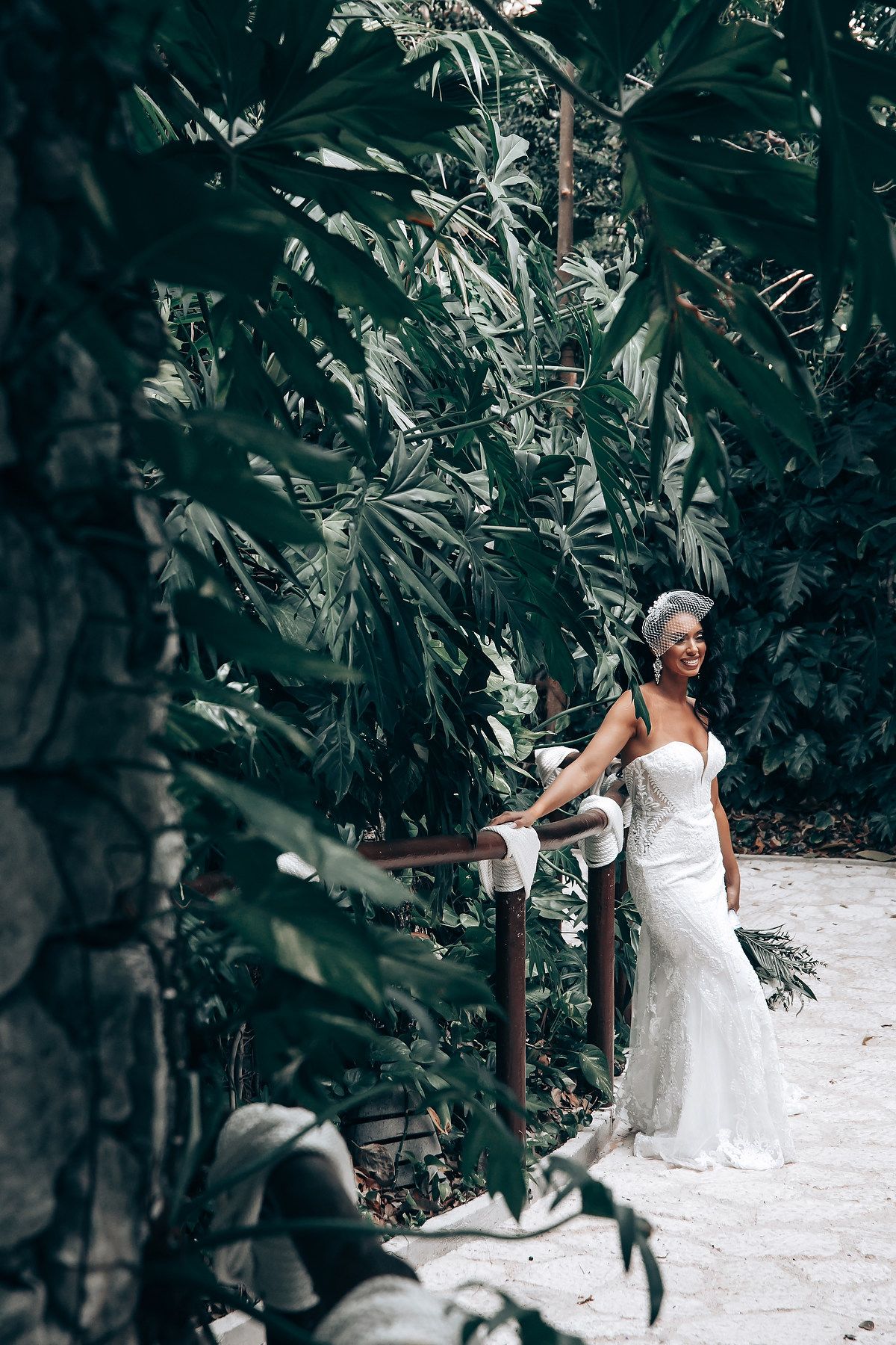 A joyful moment captured in a tropical garden setting with a flowing white wedding gown.