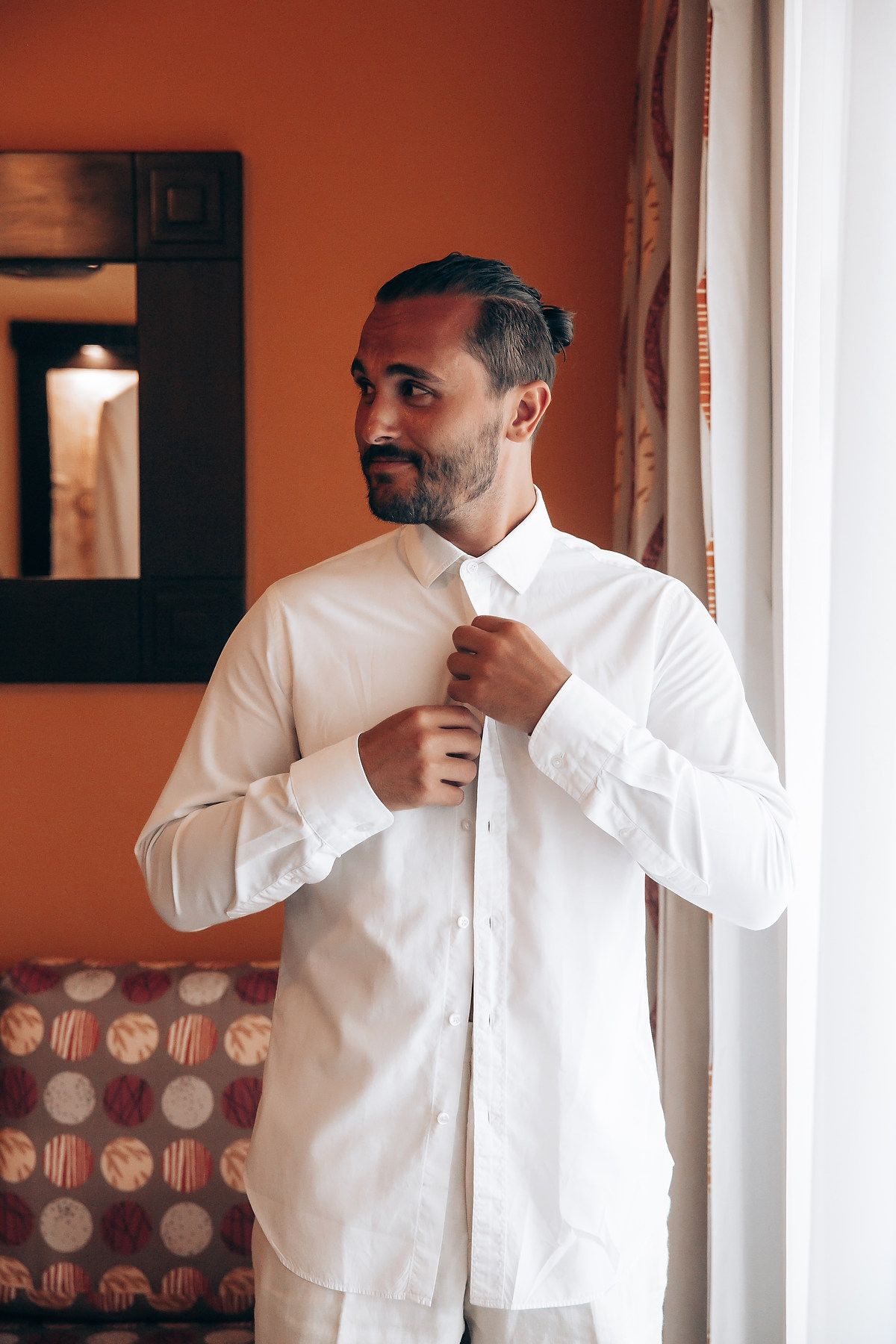 Getting ready sequence showing a person adjusting their white dress shirt collar and tie in a warm-toned room.