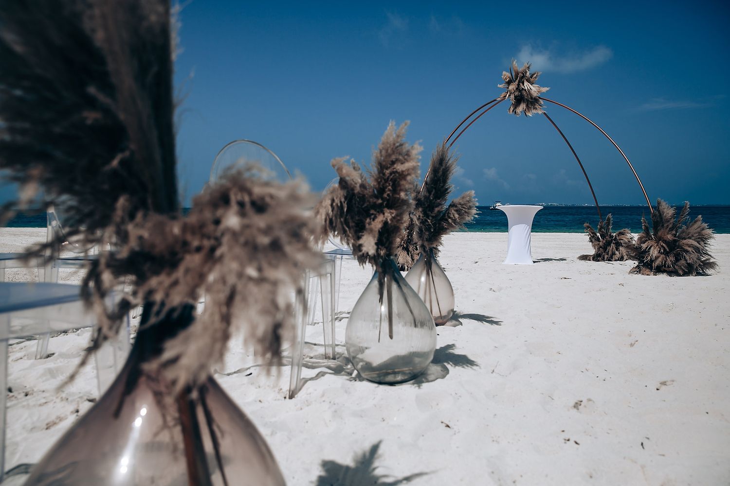 Thatched beach umbrellas line a pristine white sand beach with palm trees and turquoise ocean waters in the background.