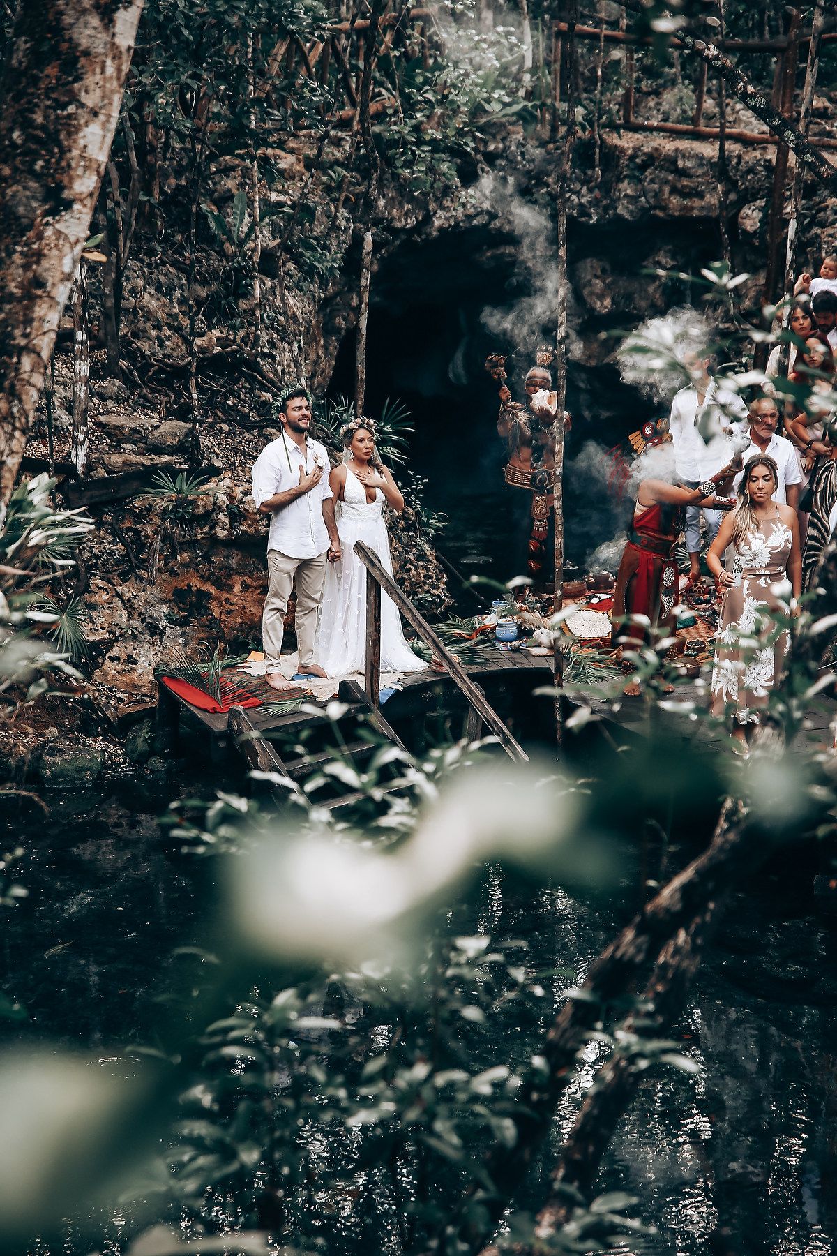 A group of people gather in a wooded area for what appears to be an outdoor celebration or event.