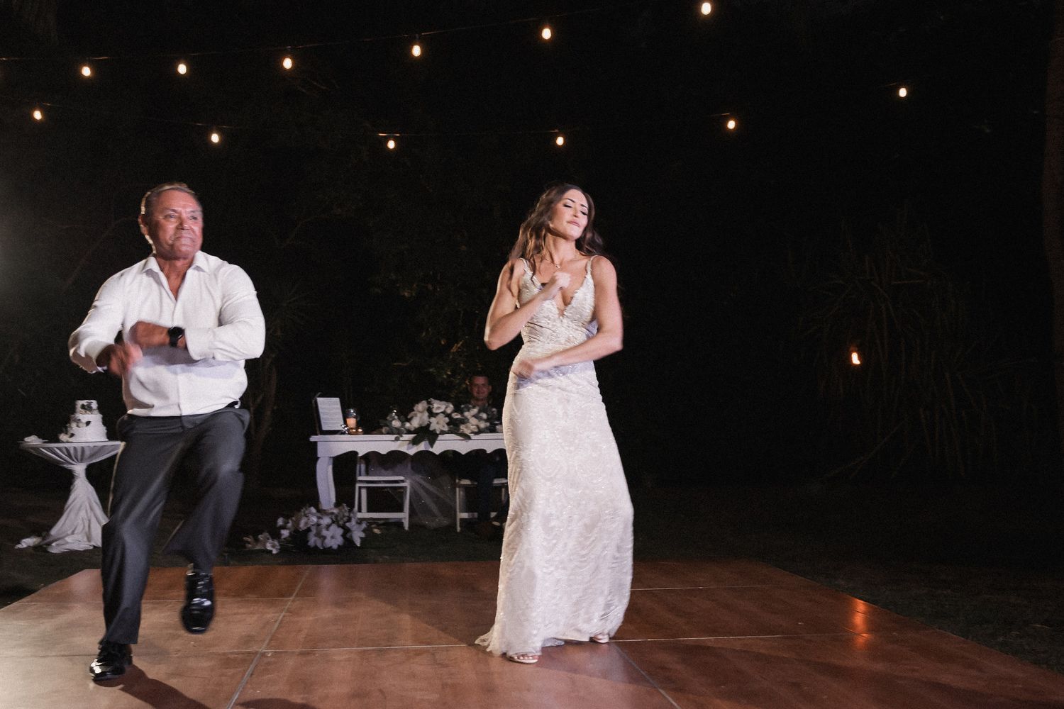 Bride and father perform fun surprise dance routine at outdoor wedding reception.