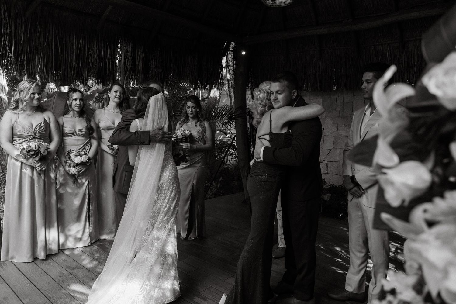 Emotional black and white photo of bride hugging father at the altar during tropical destination wedding ceremony.