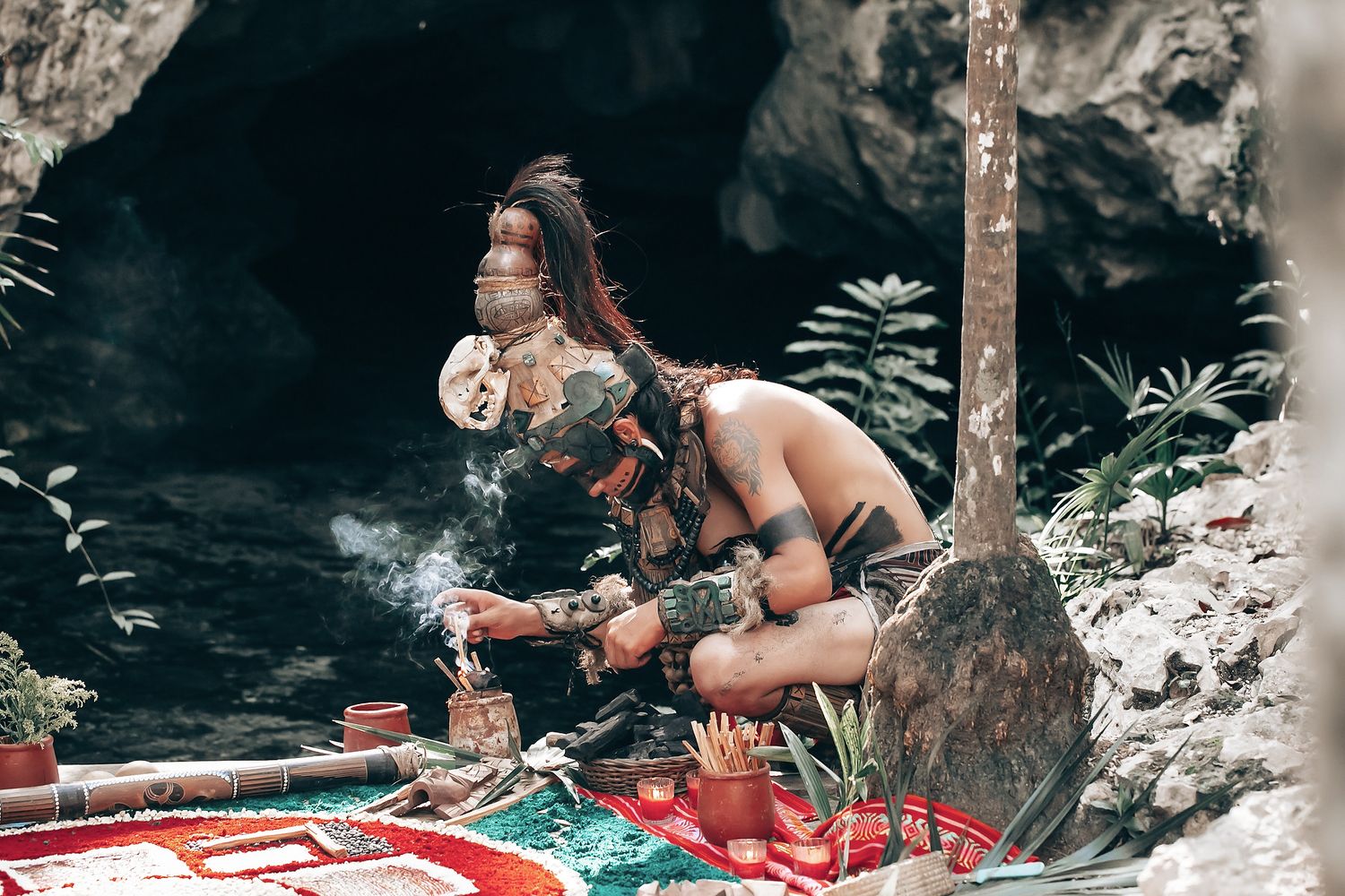 A person wearing traditional clothing sits on a boat in a tropical setting with lush vegetation.