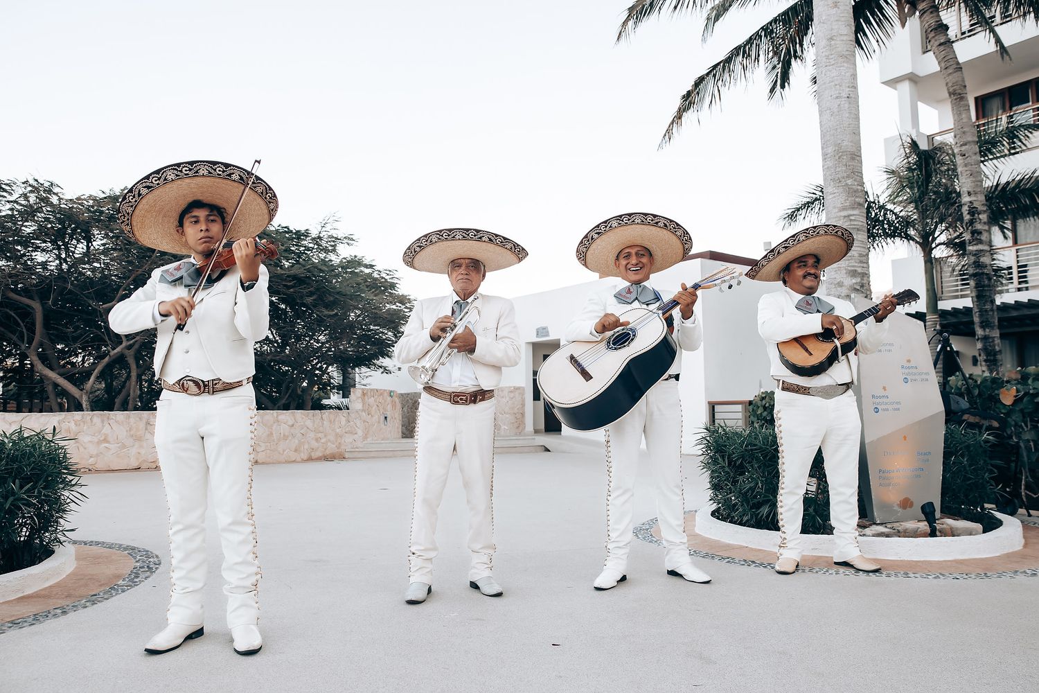 A group of mariachi musicians performing outdoors in a tropical setting.