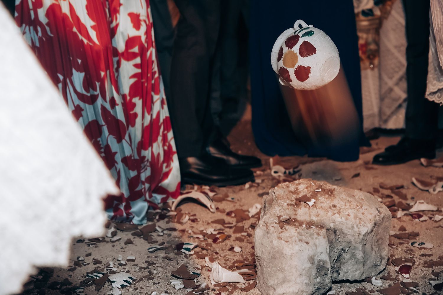 Wedding guests throw confetti during an outdoor celebration at dusk.