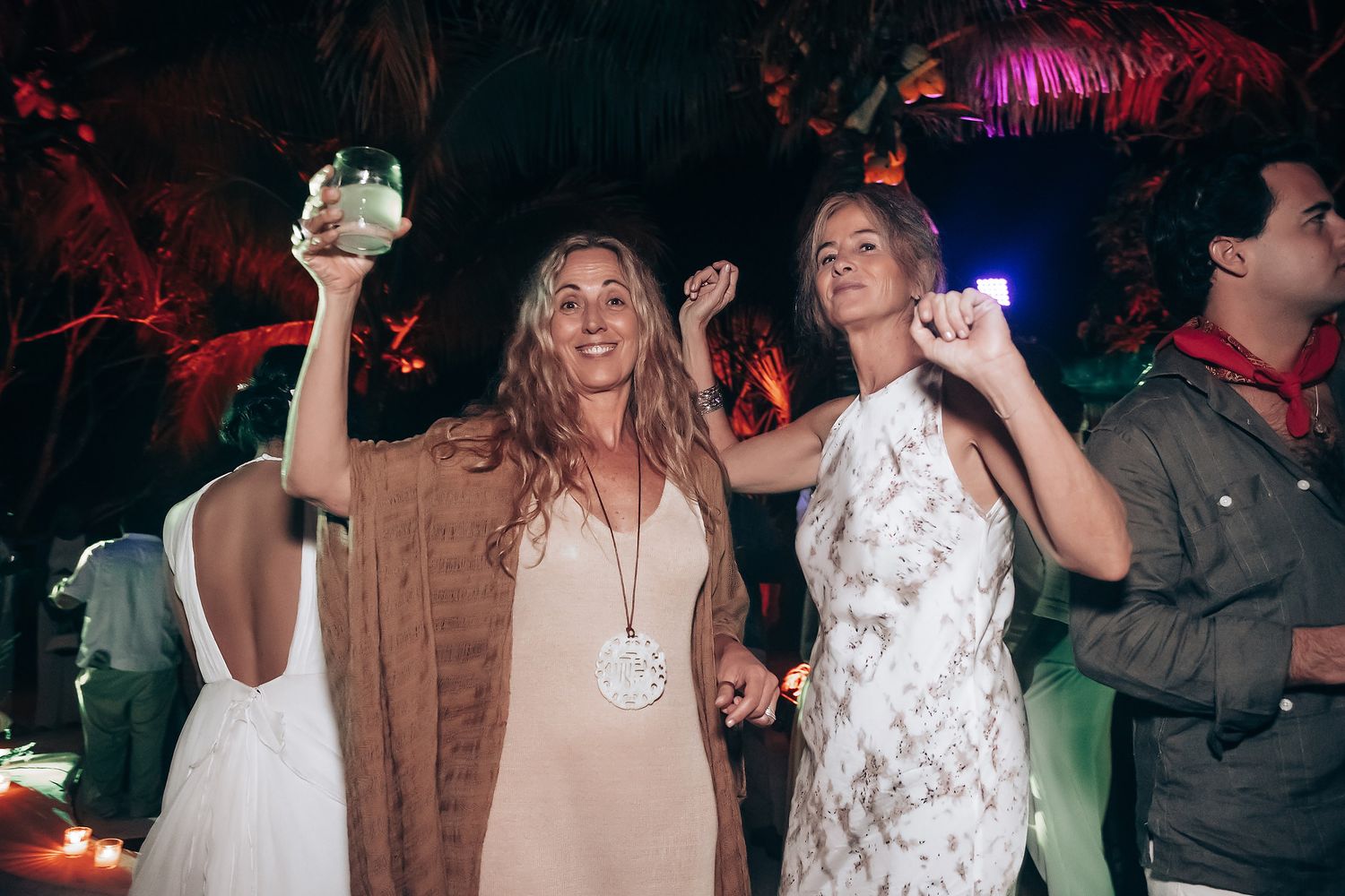 Guests enjoying themselves on a dance floor with colorful party lighting.
