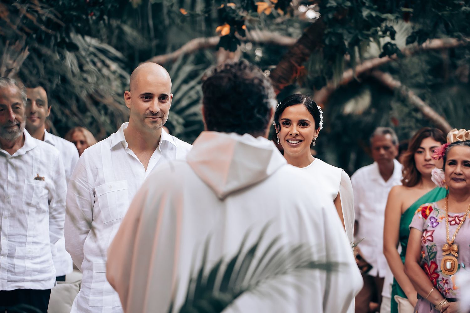 Wedding guests in white and colorful attire gathering for an outdoor celebration.