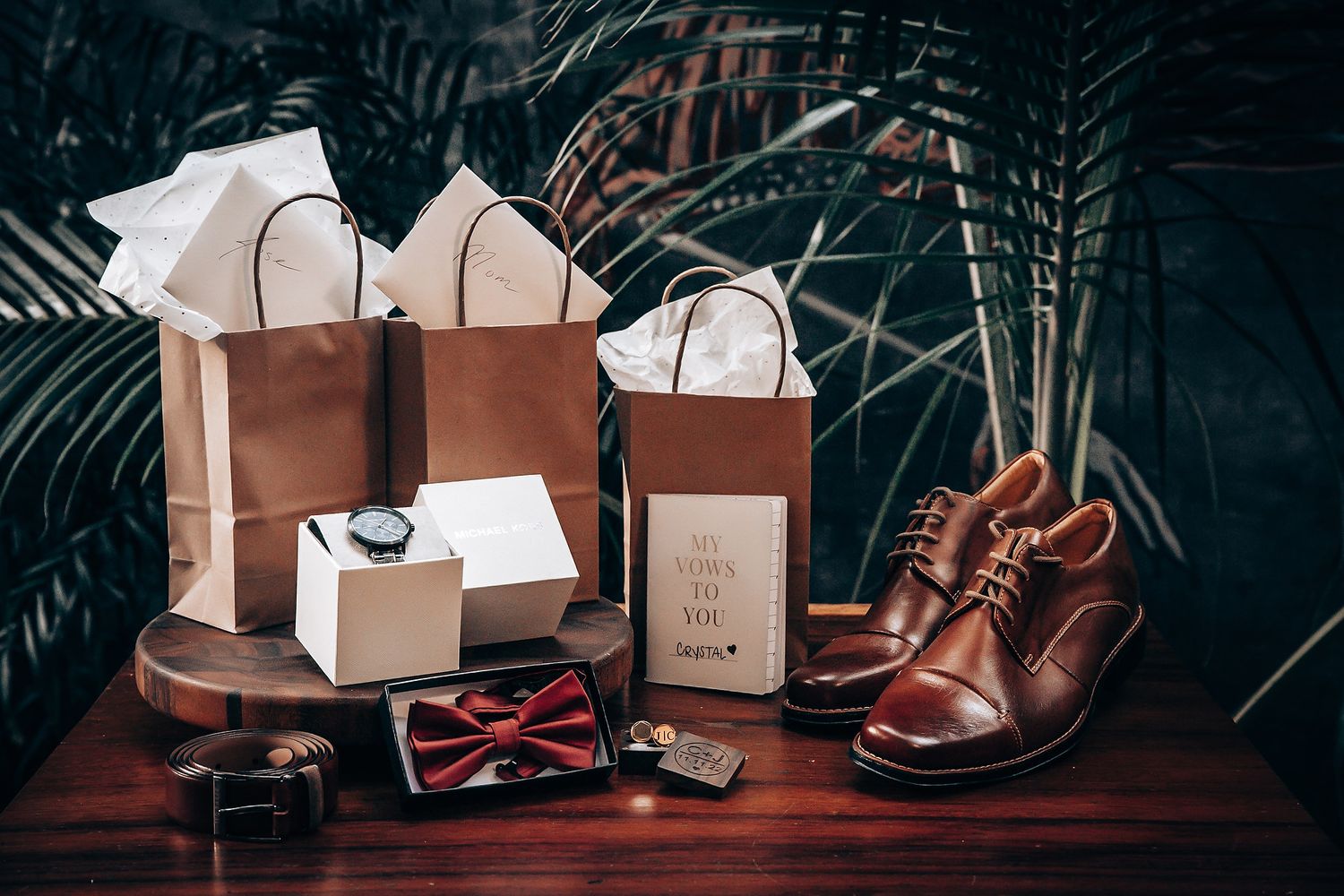 Brown leather shoes and shopping bags arranged with accessories on dark wooden surface in vintage style.