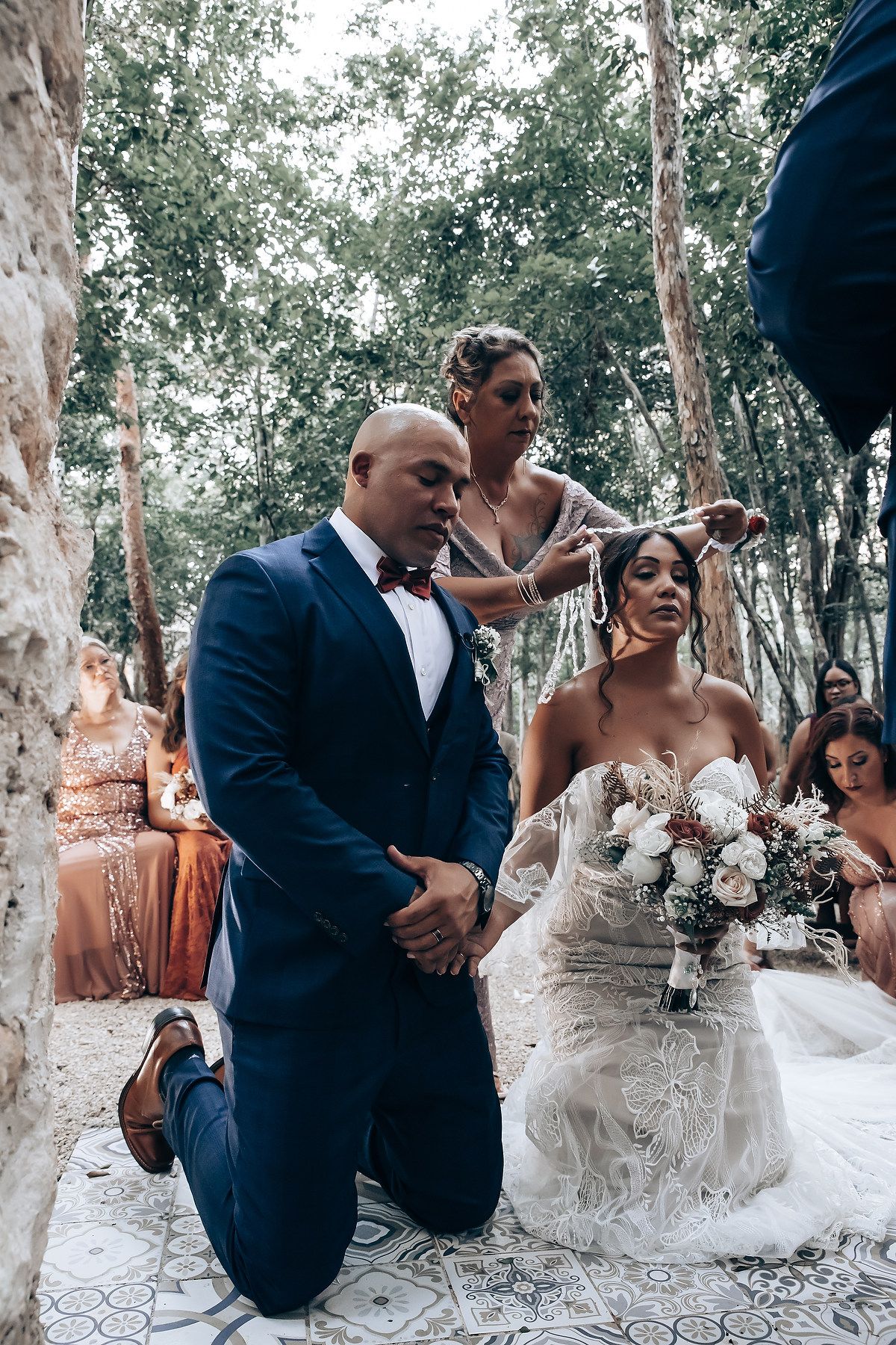 Candid moments captured during forest wedding ceremony with guests in background.