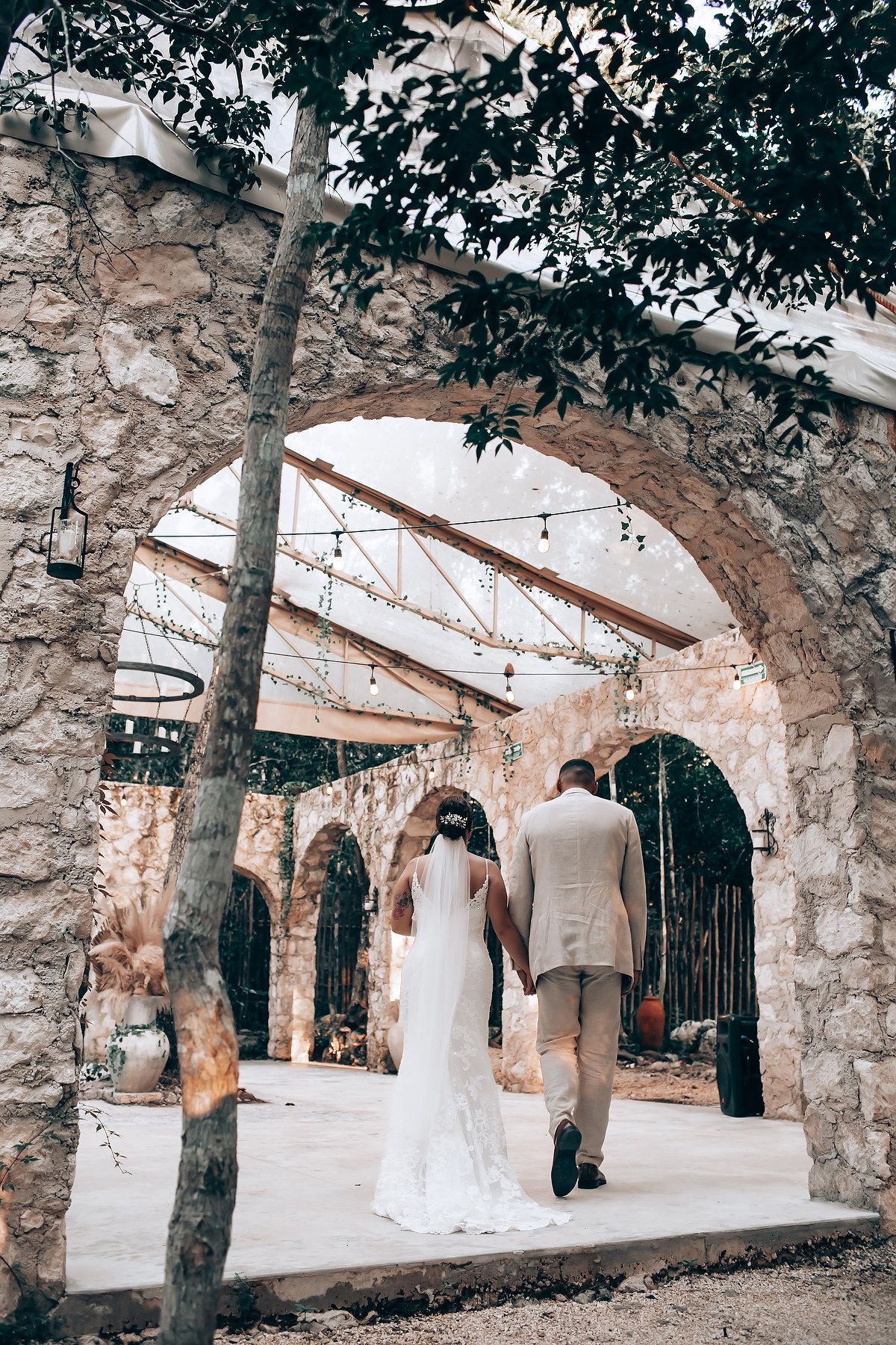 A wedding ceremony scene under stone archways with rustic architectural details.