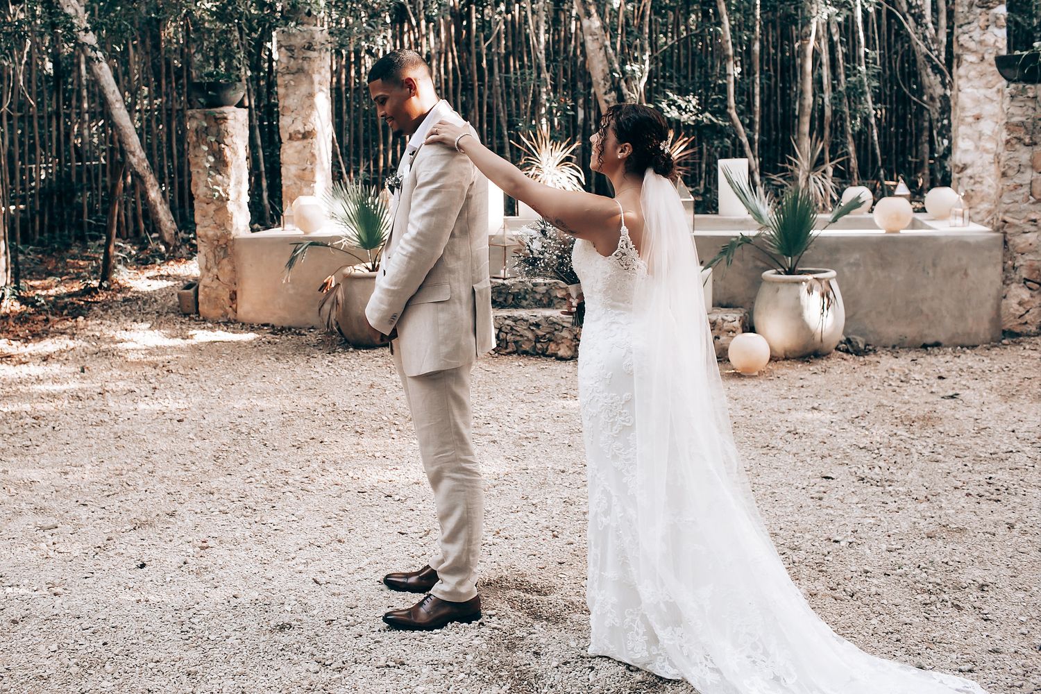 Romantic outdoor wedding ceremony setup in a wooded area with white decor.