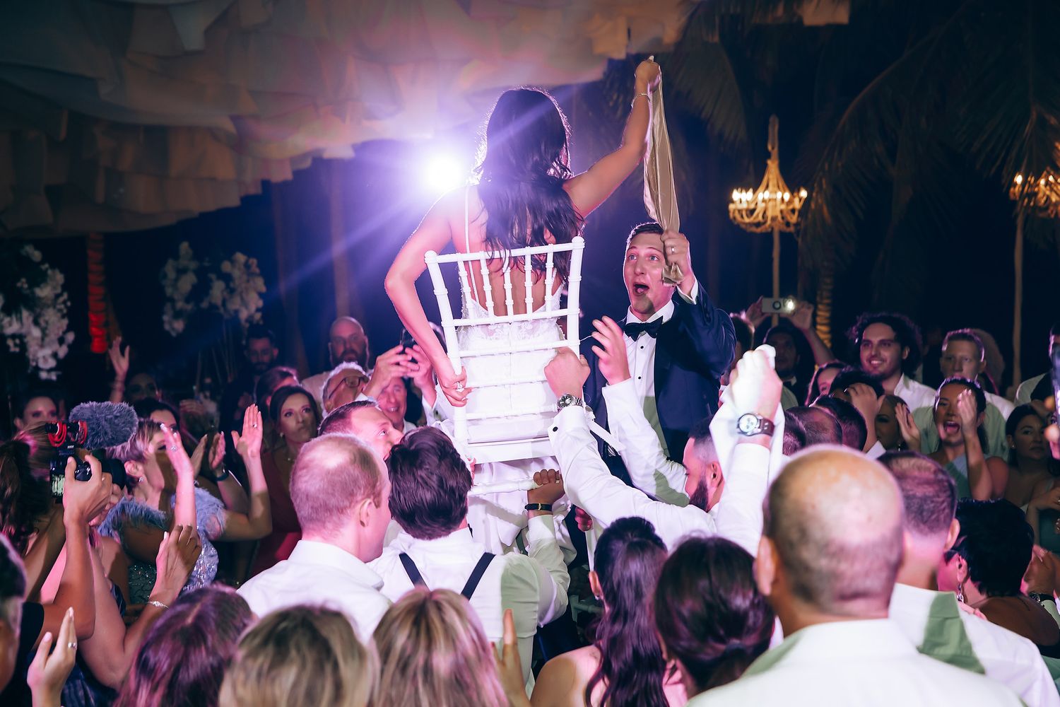 Lively dance floor scene with purple lighting under white draped ceiling.