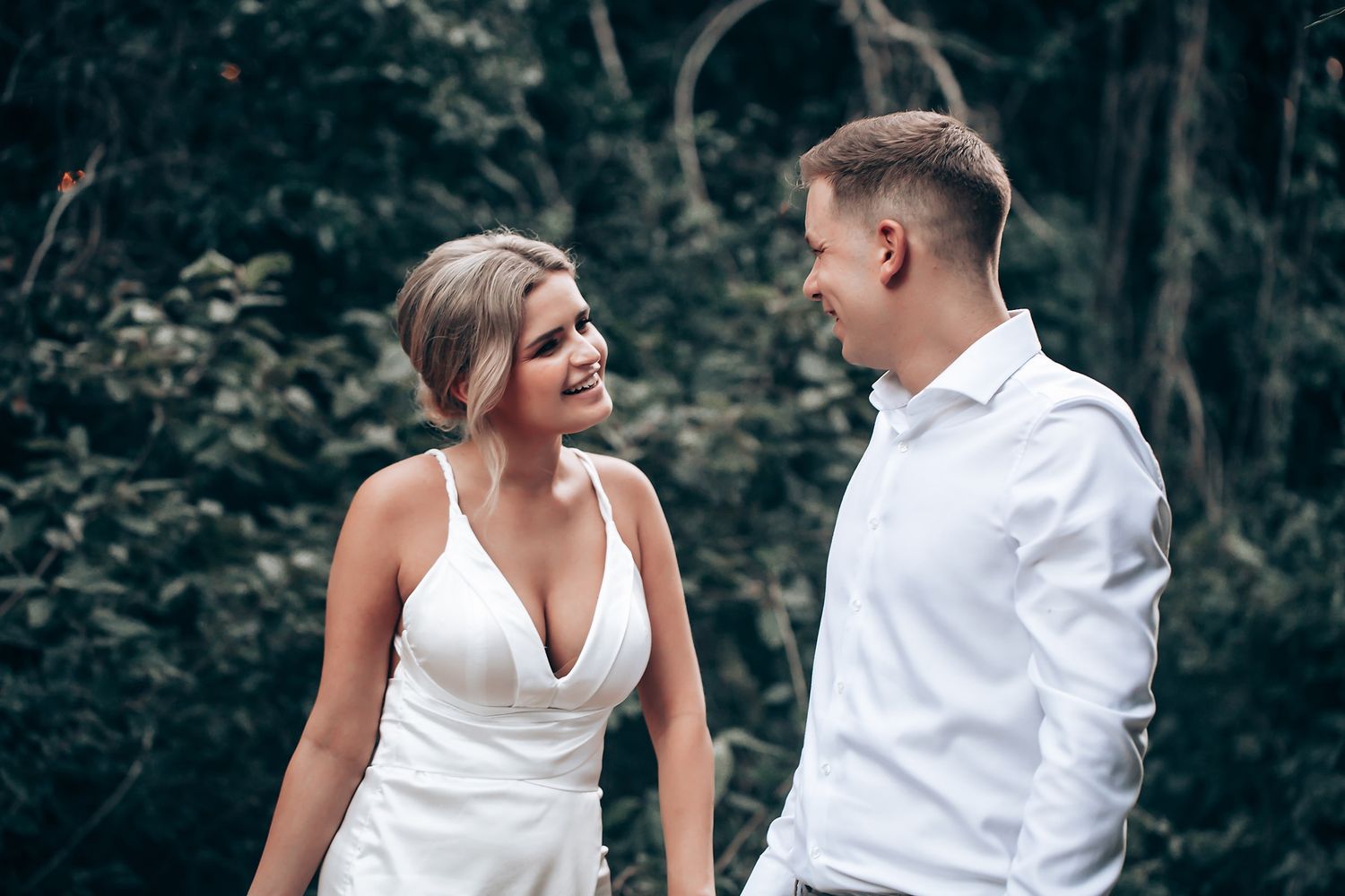 Newlyweds share an intimate dance moment in a lush garden with artistic blue wall backdrop.