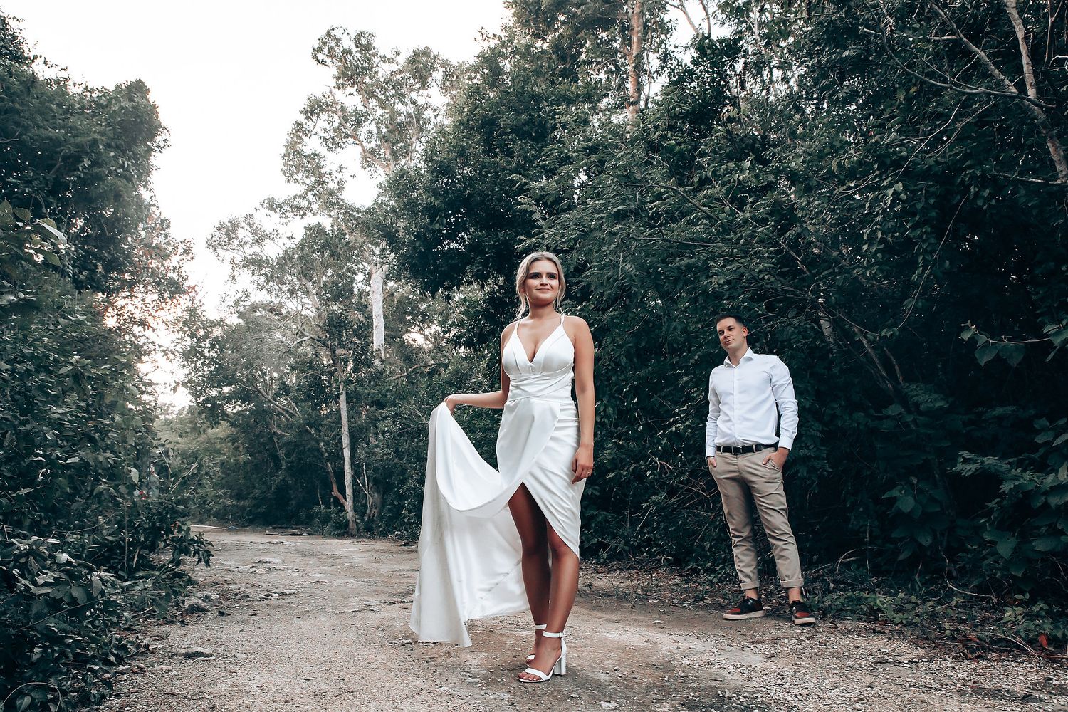 Artistic wedding photography captured on tree-lined path in natural setting.