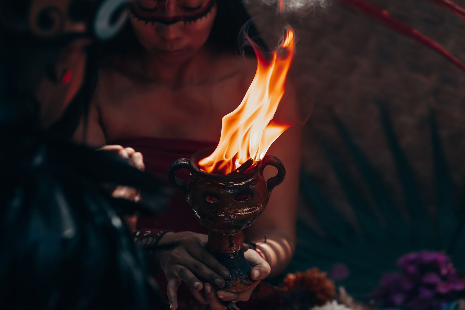 Sacred fire ceremony with burning copal and ritual offerings in a dark setting.
