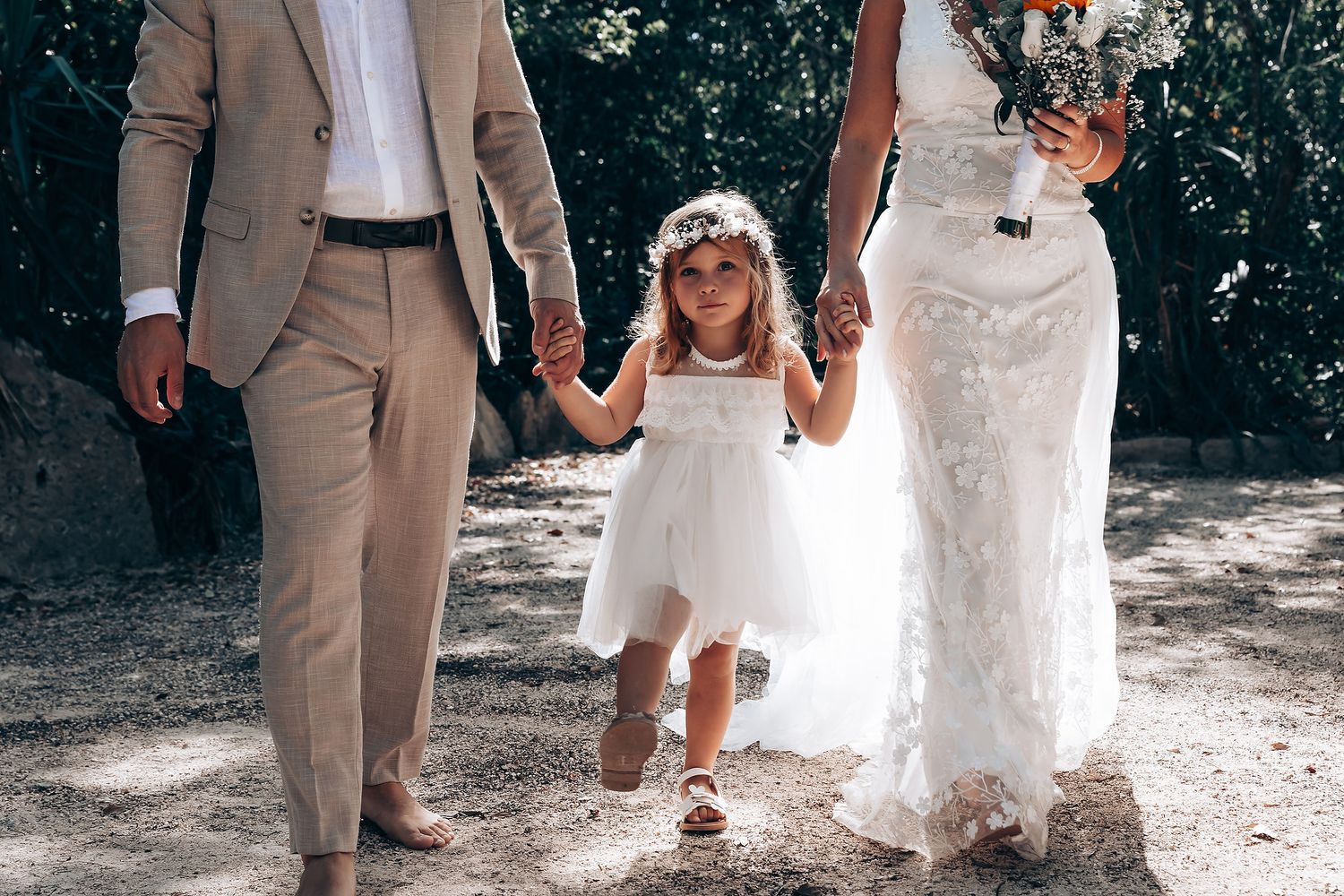 Wedding guests in formal attire walking along a natural stone pathway.