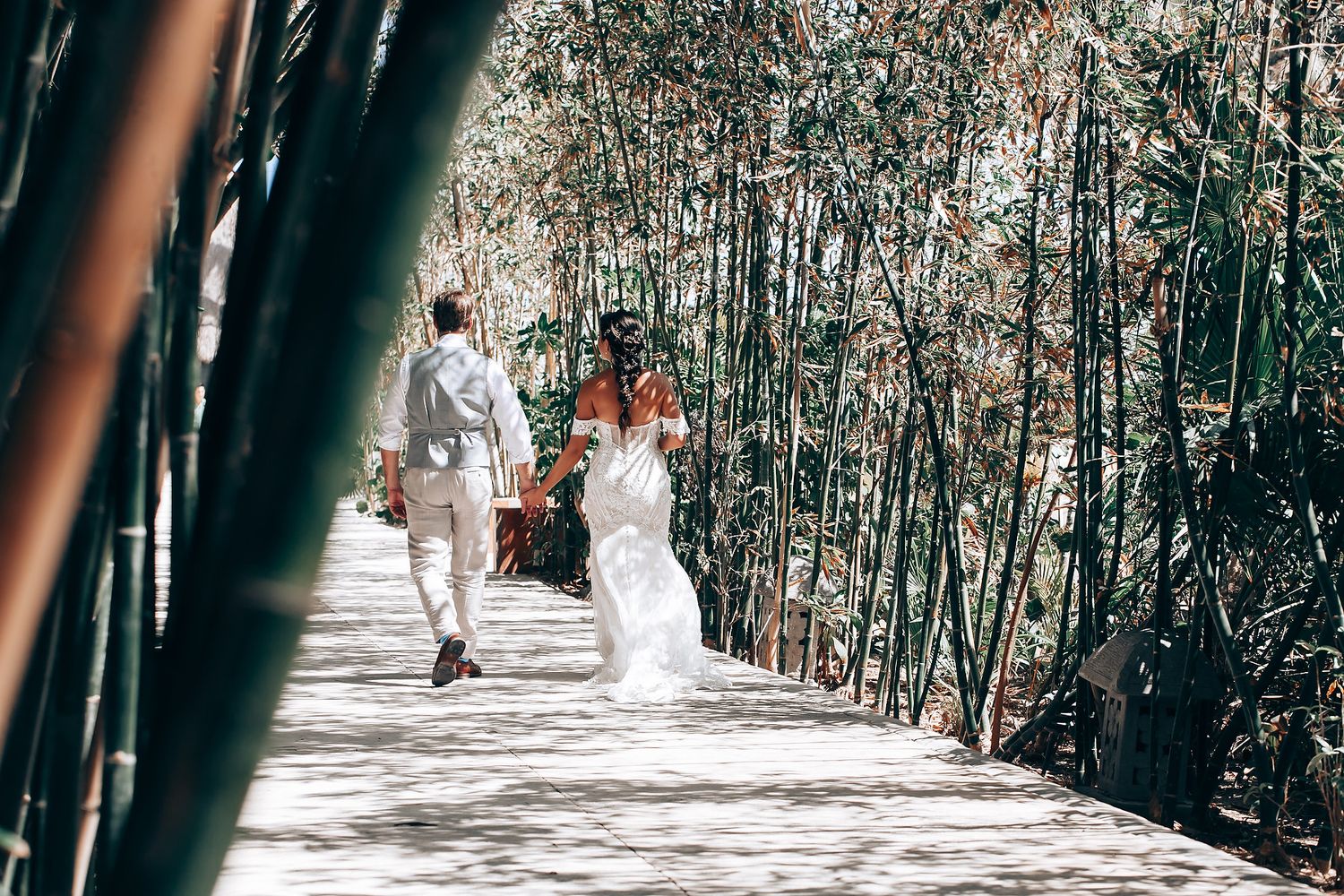 Wedding party walking through natural bamboo forest pathway.