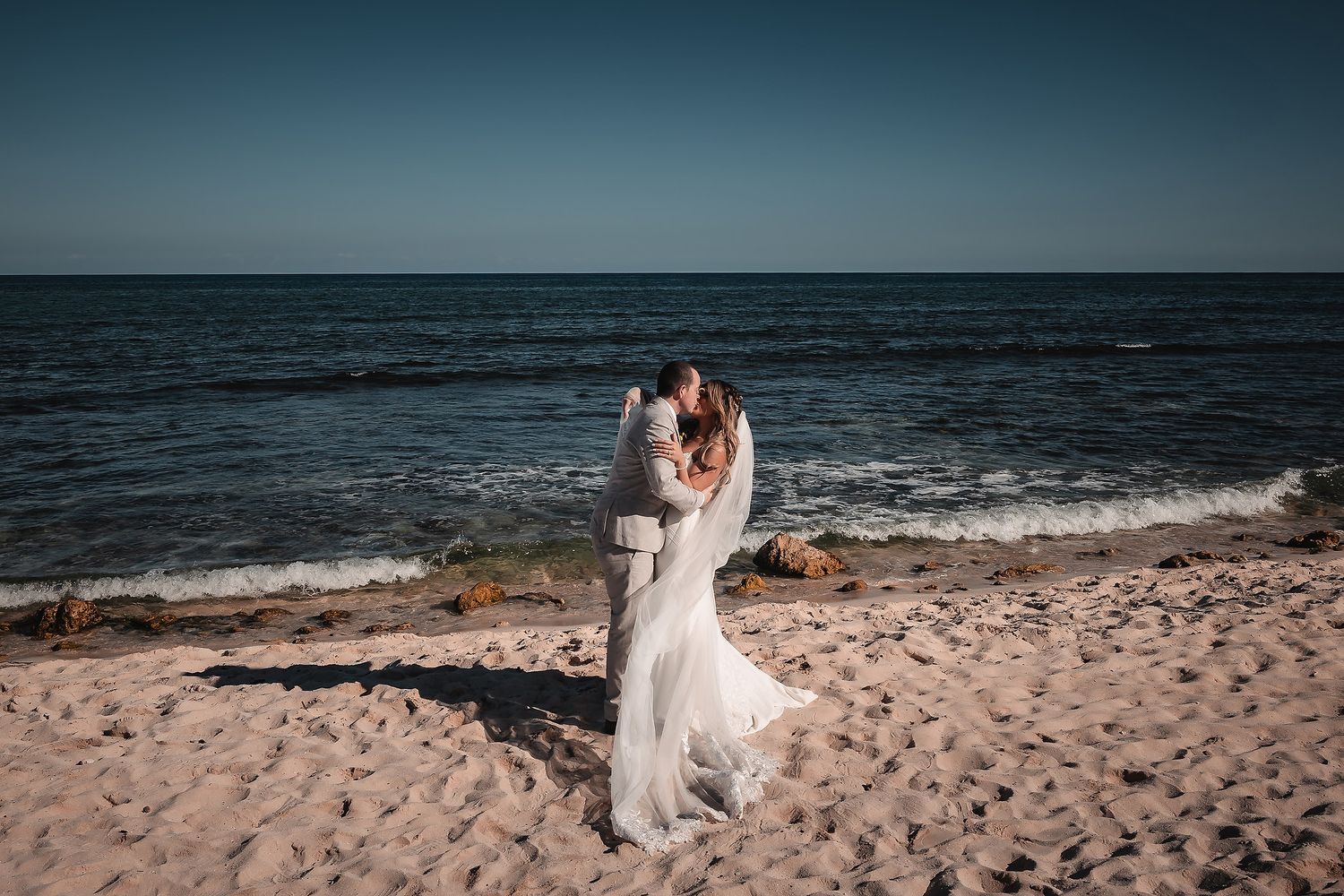 A romantic beach wedding photoshoot with waves crashing in the background.