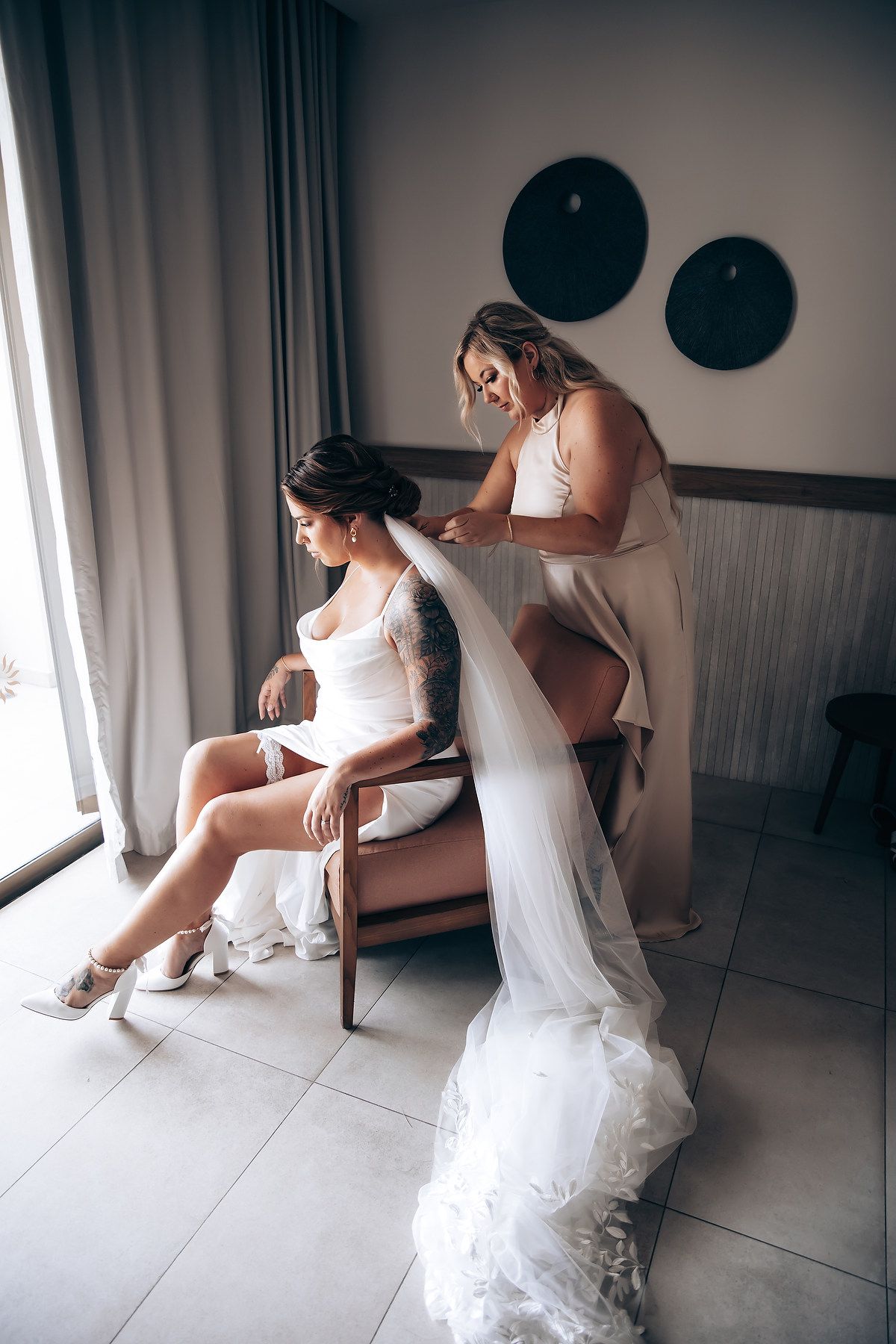 A series of intimate getting ready moments in a hotel room showing a bride in her white wedding dress.