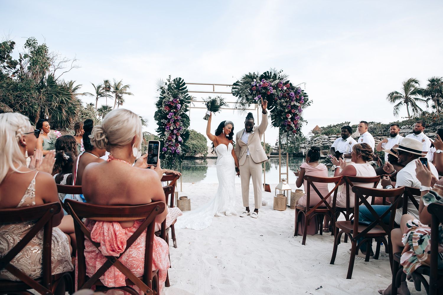 Guests attending outdoor beach wedding ceremony with wooden cross-back chairs.