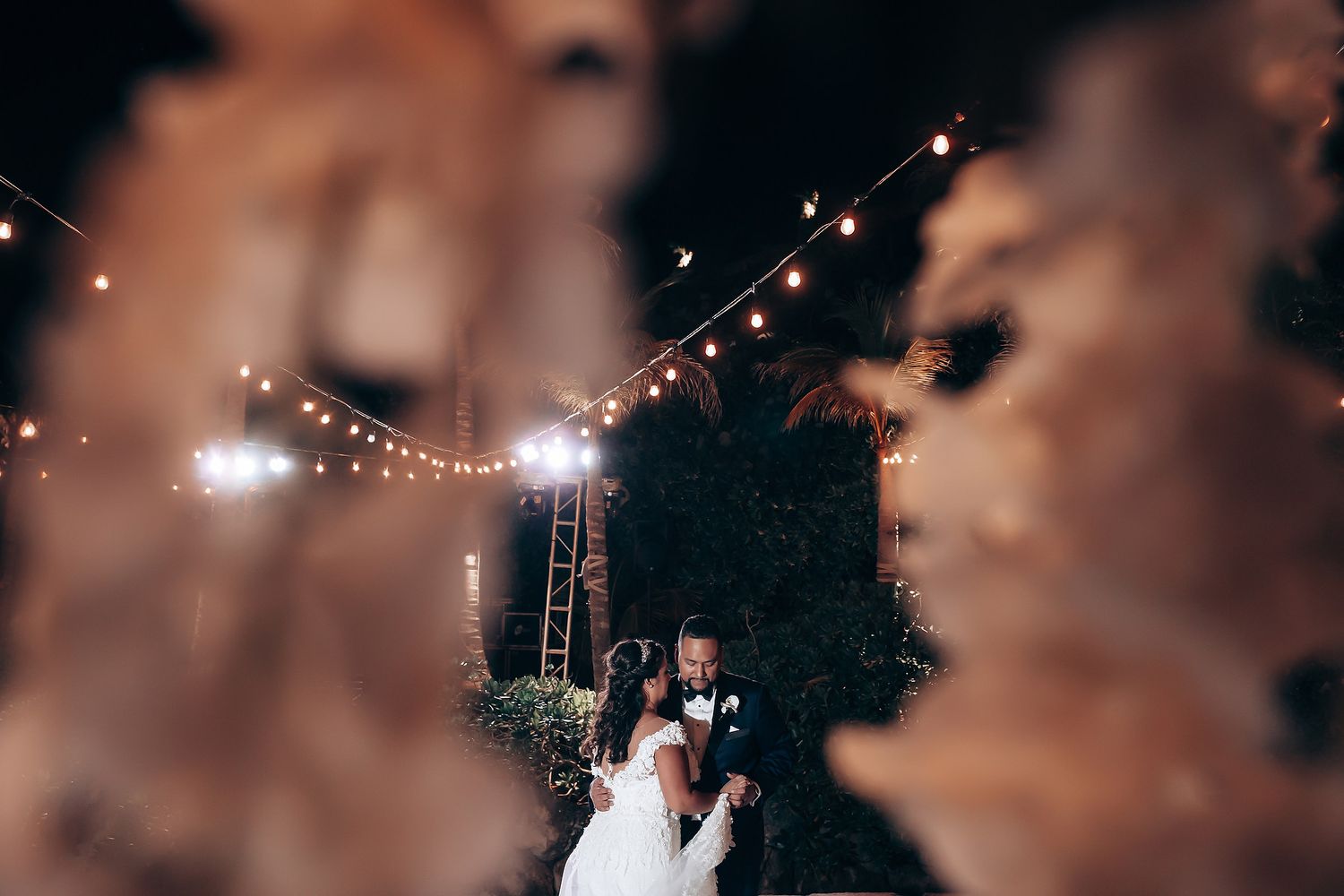 Romantic outdoor wedding reception with twinkling string lights and floral decorations.