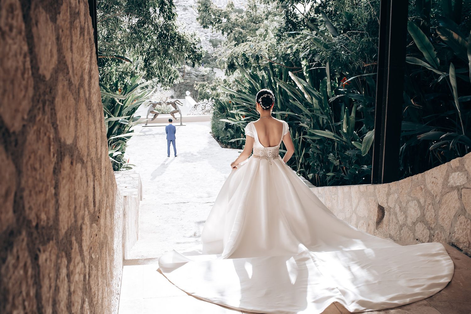 White wedding dress displayed against a rustic stone wall backdrop.